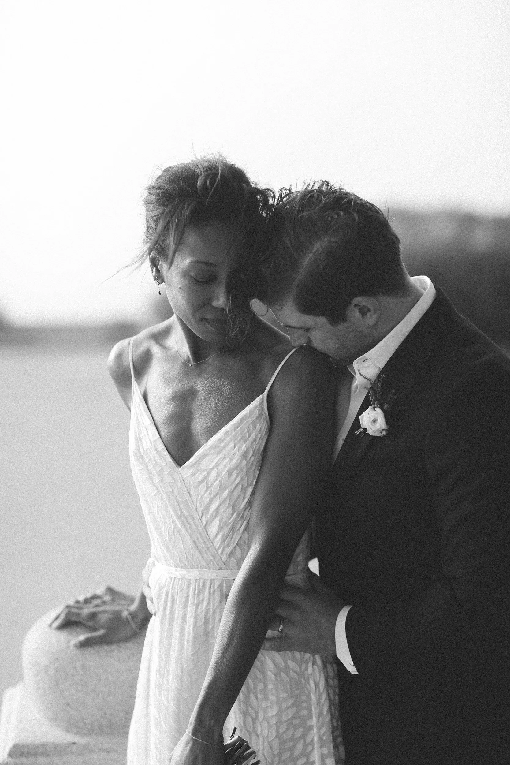 a biracial couple on their wedding day with the husband kissing his wife's shoulder from behind, sex therapy, couples therapy
