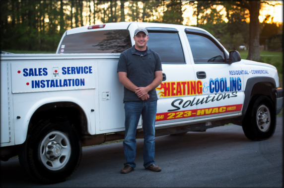 Owner of Heating and Cooling Solutions of Greenwood, SC Inc. standing next to a white truck with service and sales info for Heating and Cooling Solutions of Greenwood, SC Inc., during sunset in an outdoor setting.