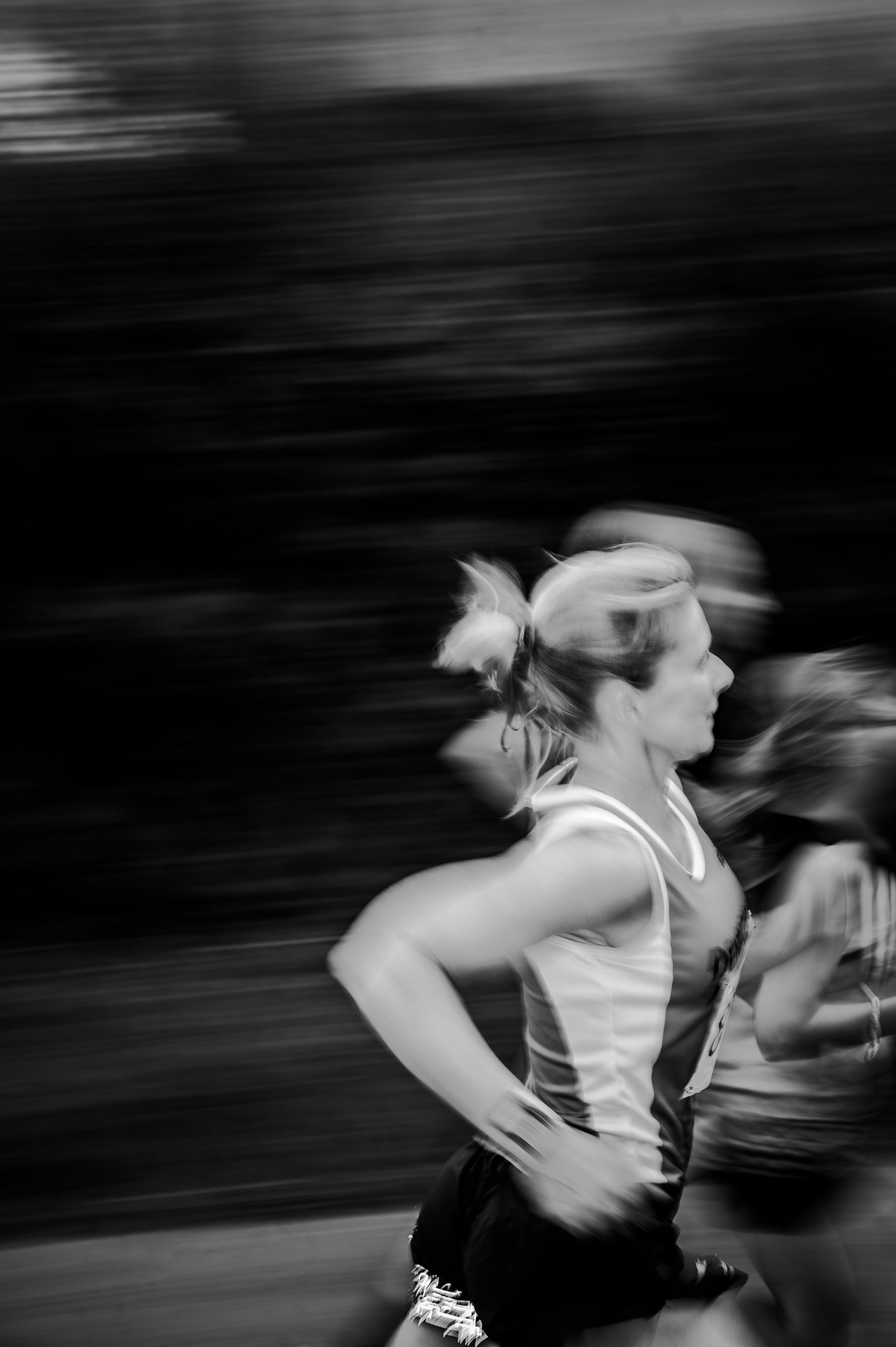 Black and white photo of a woman running, with motion blur in the background.