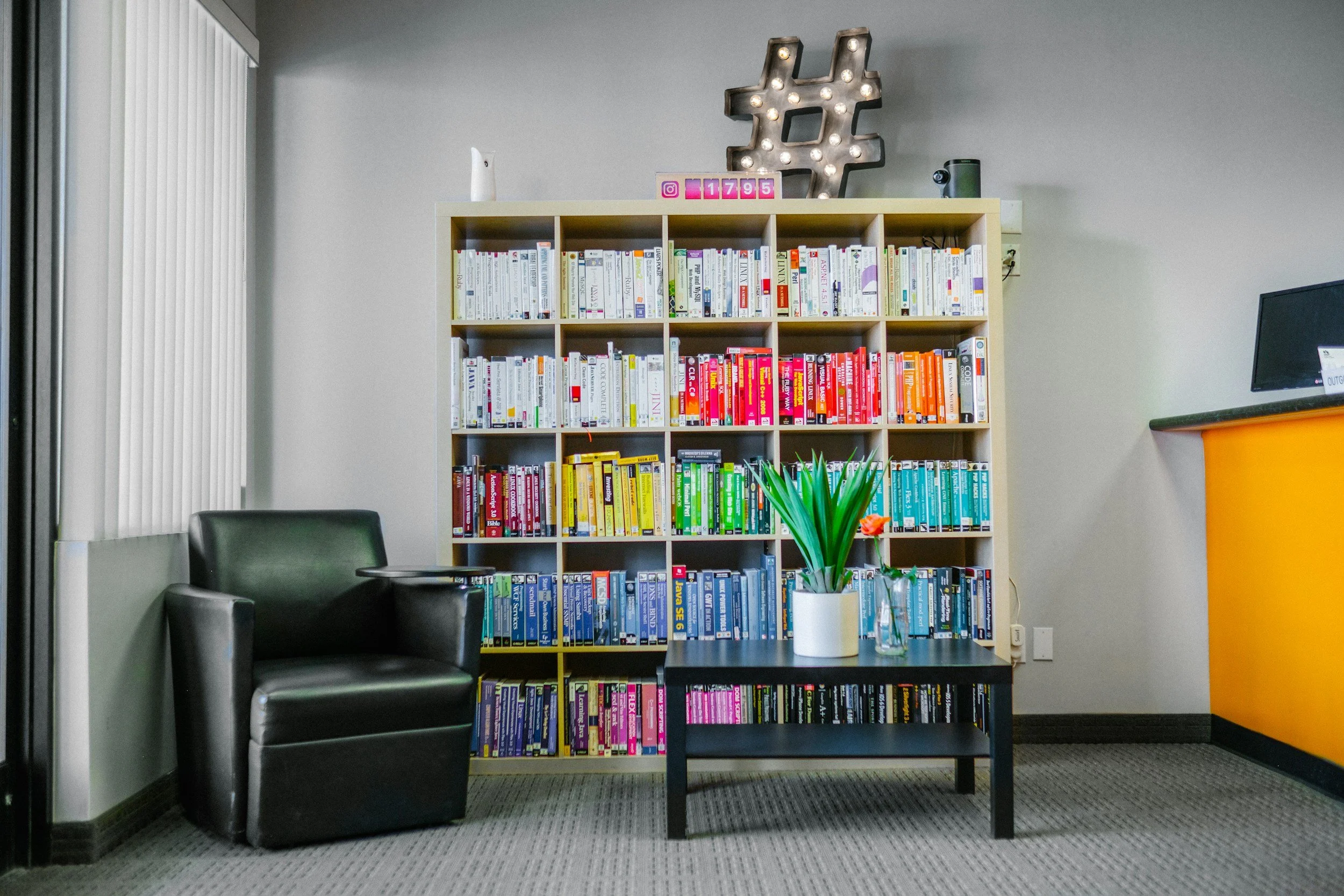 Modern office interior designed in Austin a bookshelf, black leather chair, indoor plants, and minimalist decor