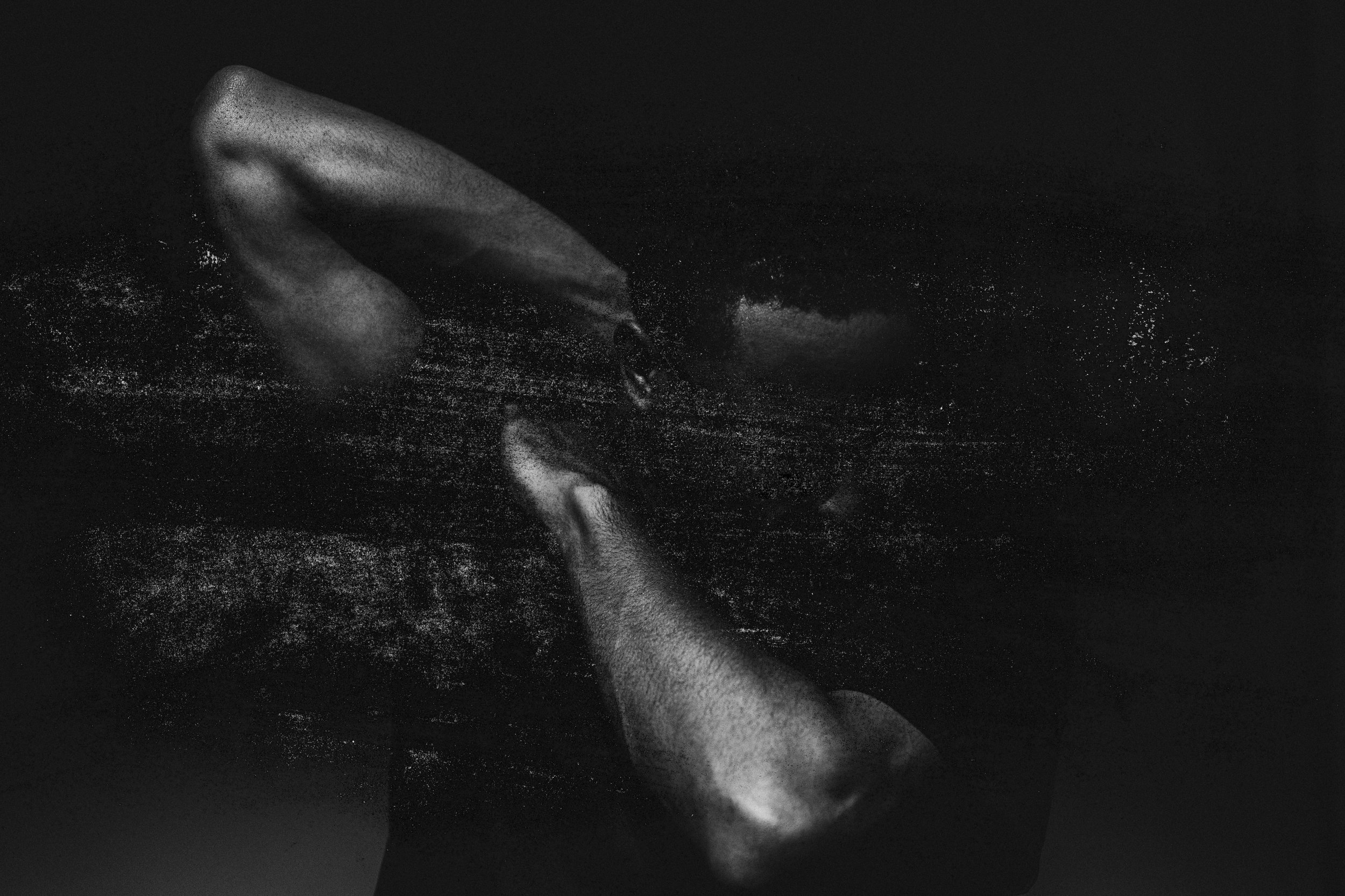 Schwarz-Weiß-Aufnahme einer schwarzen Person. Impulsive Armhaltung. Starke Textur.