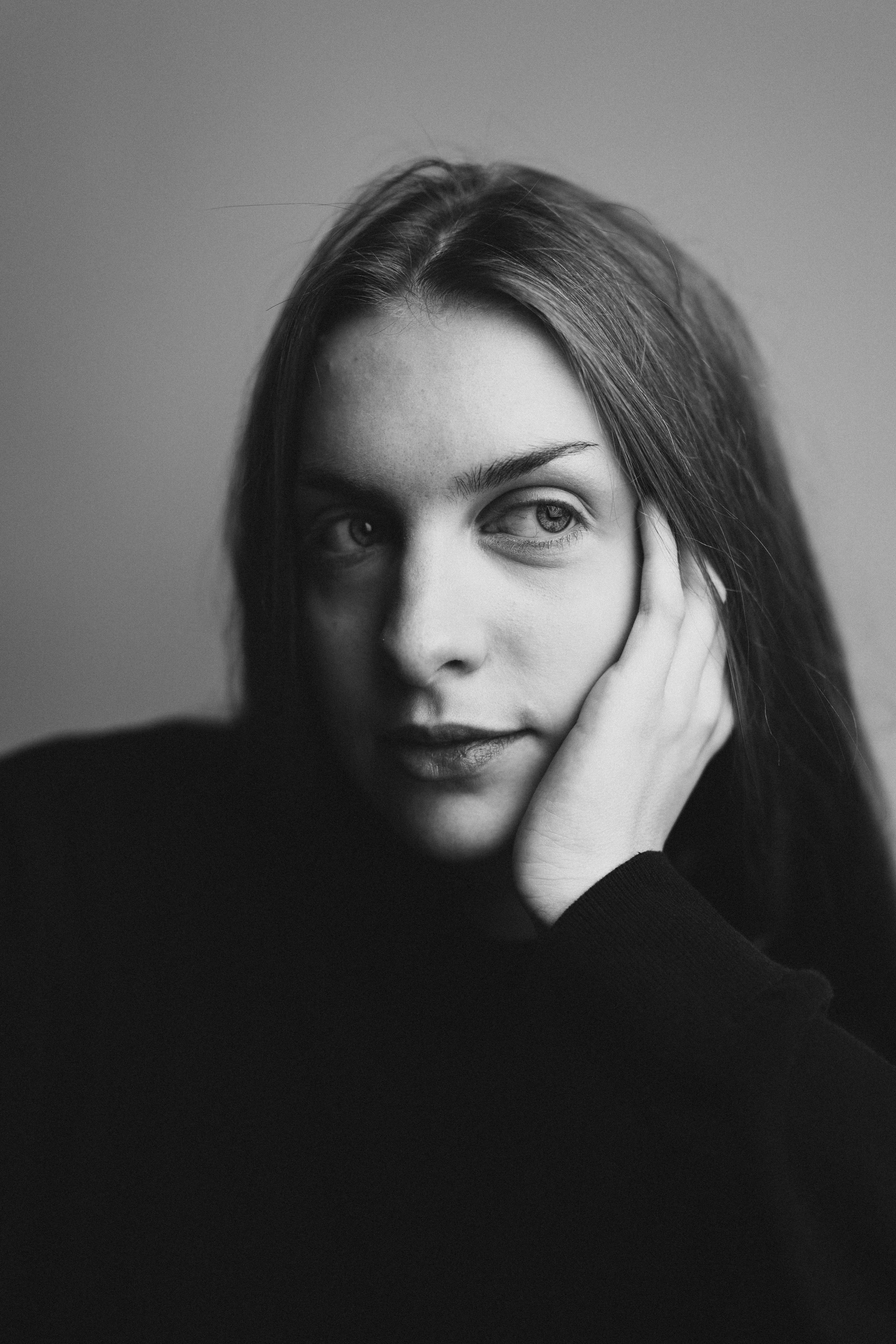 Schwarz-Weiß-Fotografie einer Frau, die mit der Hand ihr Gesicht stützt und seitlich blickt.