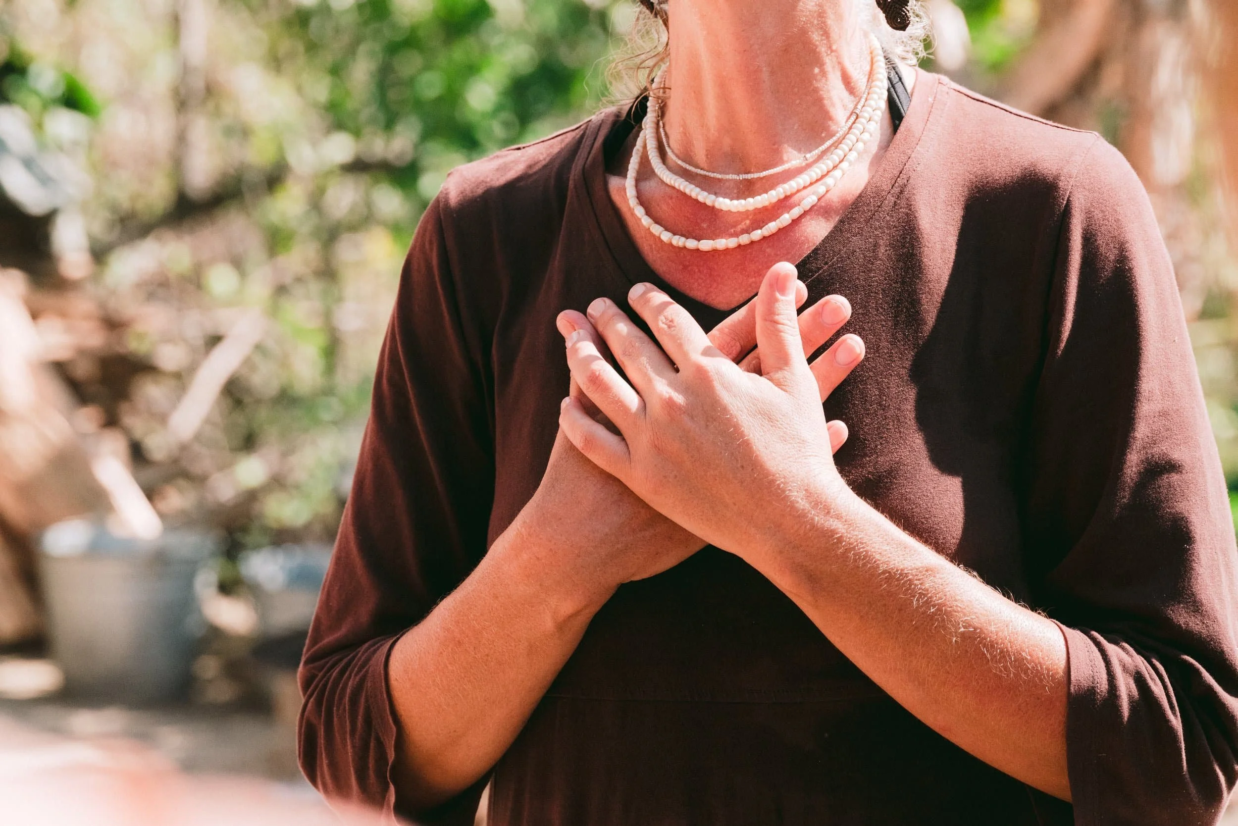 A woman clasping her hands together and holding it to her chest