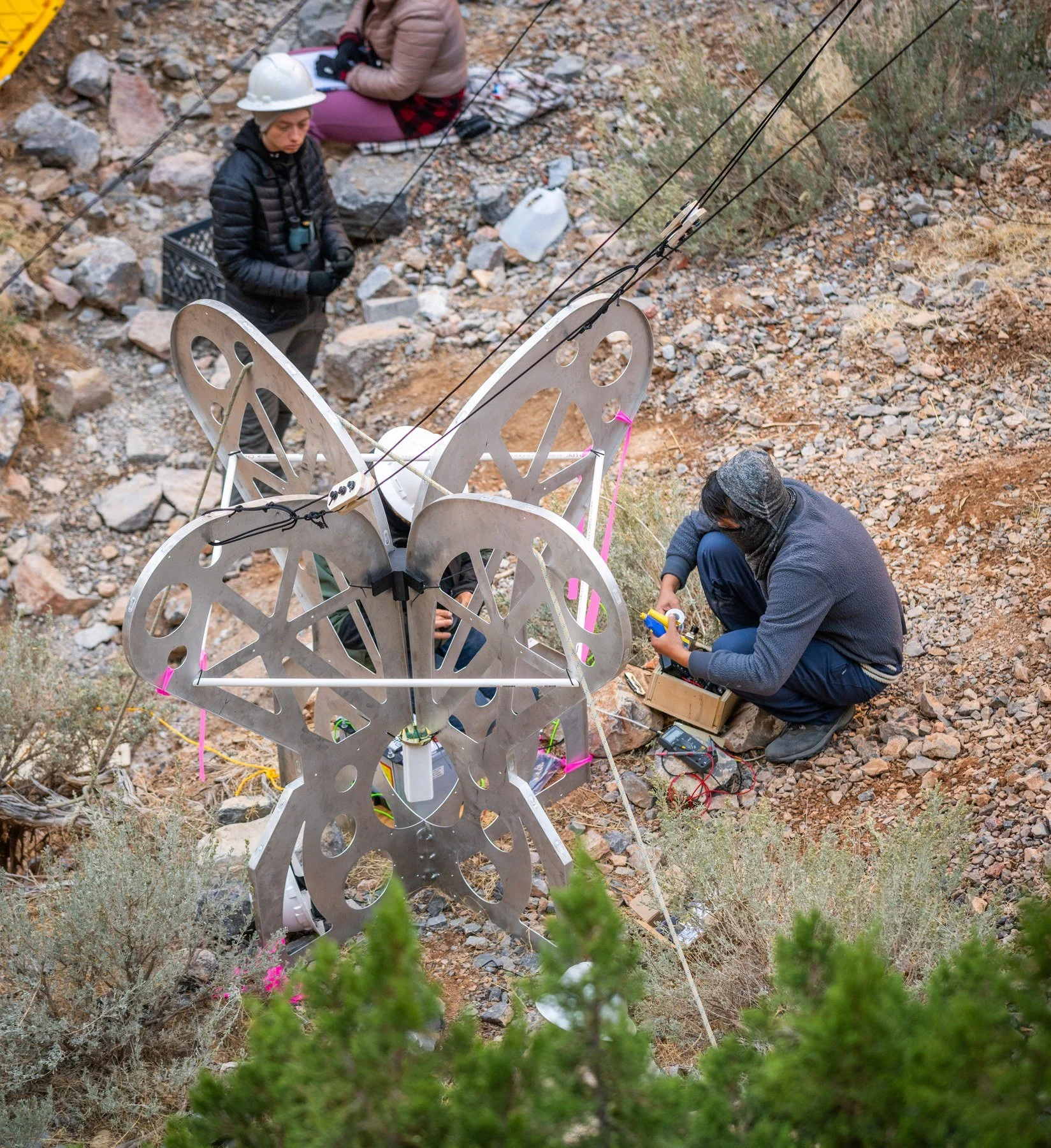 Field team working around a research antenna and rigging in a canyon.
