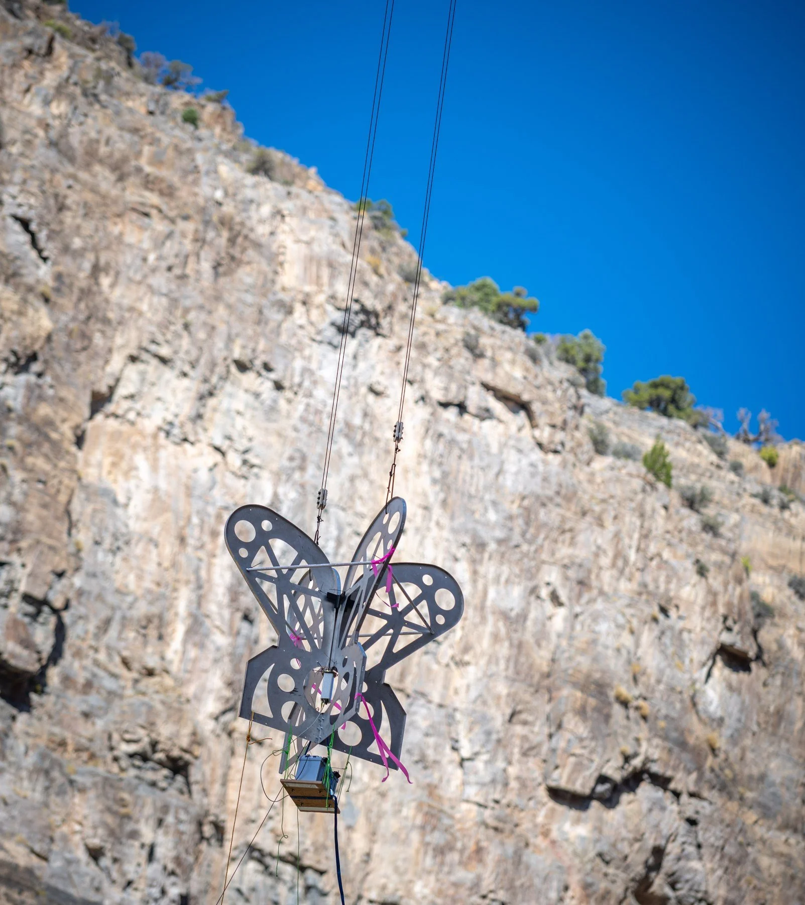 Research antenna suspended on rigging against a canyon wall.