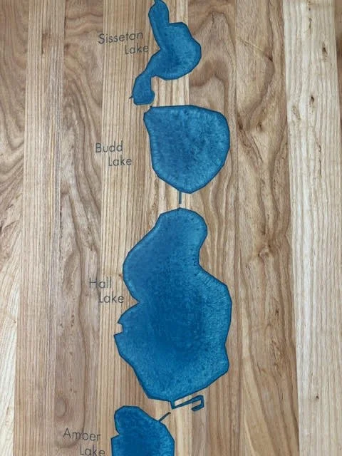 Close-up of a handcrafted wooden lake map featuring blue inlays of Sisseton Lake, Budd Lake, Hall Lake, and Amber Lake in Fairmont, Minnesota.