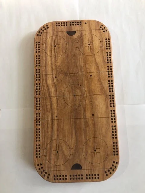 Handcrafted rectangular wooden cribbage board featuring an engraved hockey rink design and scoring holes around the edges.