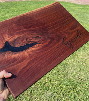 Dark wood charcuterie board with a natural live-edge detail, distinctive wood grain, and a personalized name engraving.