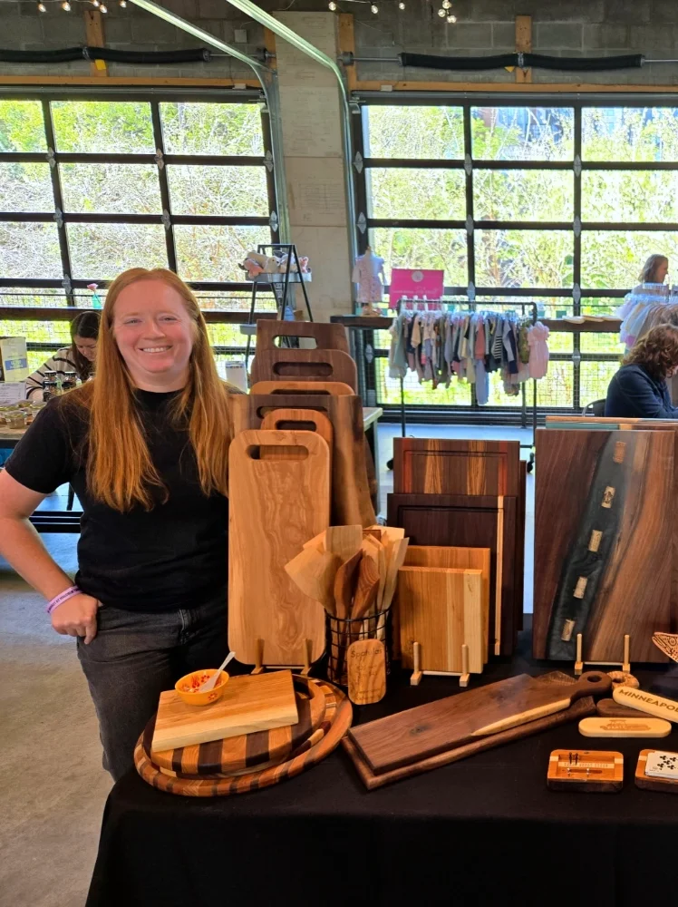 Sam at a vendor show standing by her display table
