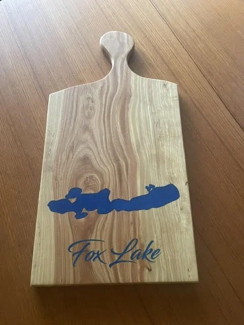 Personalized wooden serving board with a rounded handle, blue Fox Lake map inlay, and engraved Fox Lake lettering.