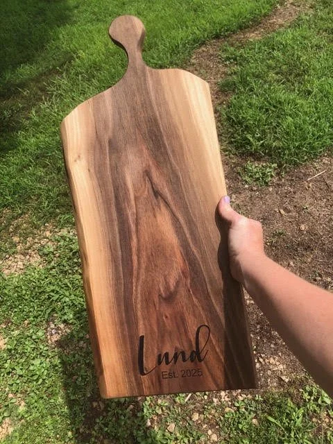 Handcrafted wooden charcuterie board with contrasting natural wood grain, a rounded handle, and a custom Lund Est. 2025 engraving.