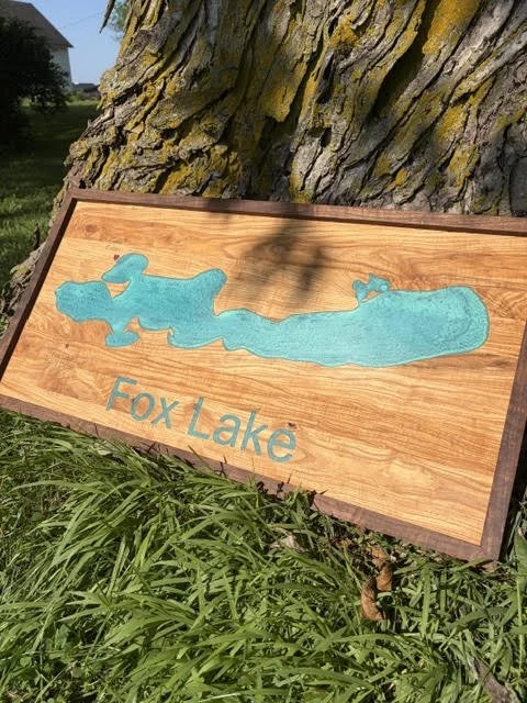 Custom framed wooden Fox Lake sign with a turquoise blue lake inlay, photographed outdoors against a tree.