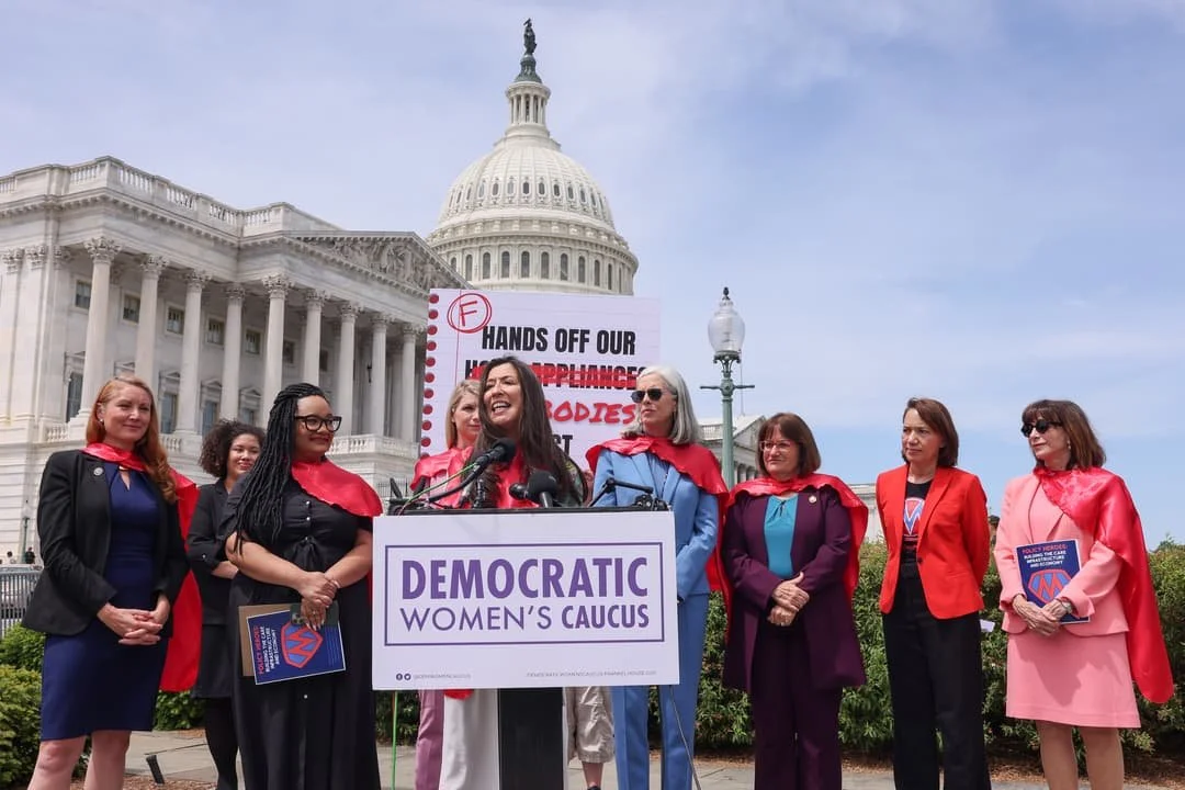 Democratic women in Congress around a podium at a press conference in front of the US Capitol