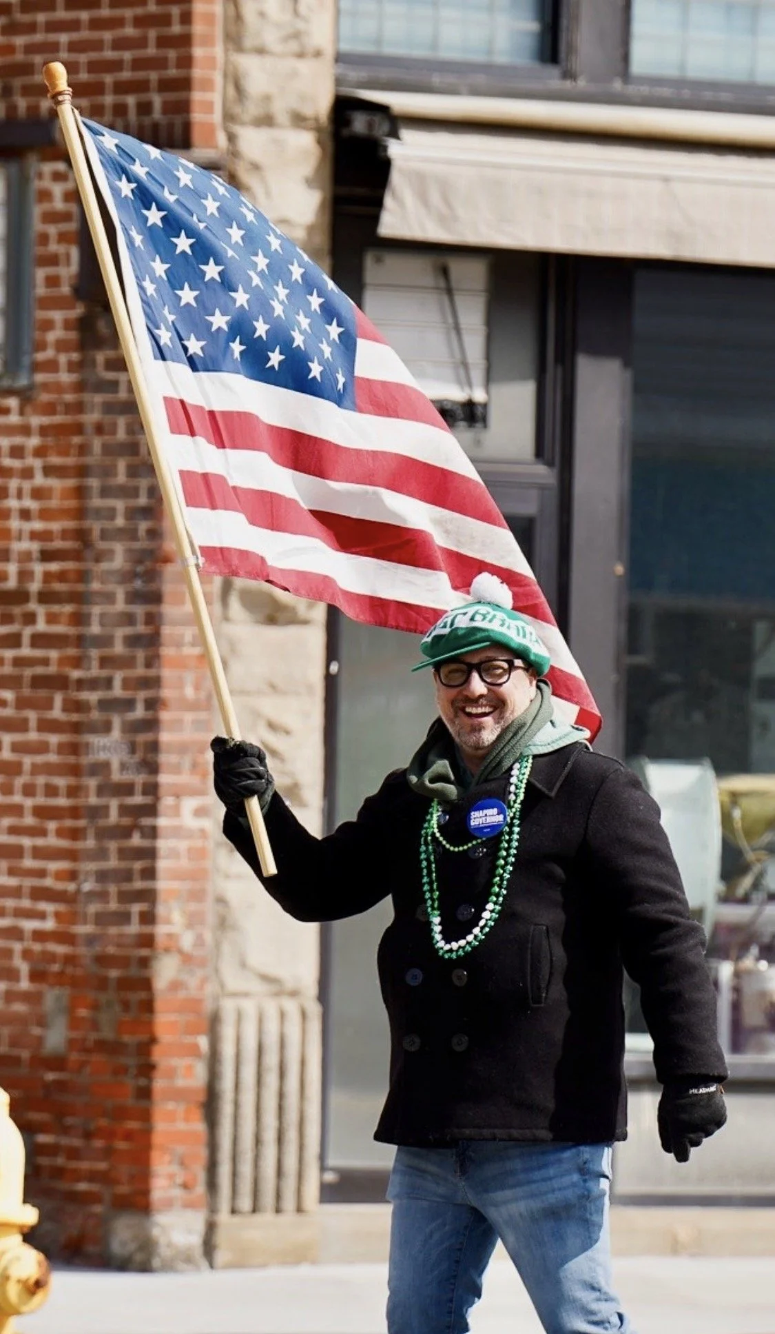 Photo of Jim Wertz with a green hat holding an American flag.