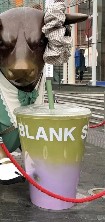 A giant Blank Street Macha drink in front of a giant bronze bull in Birmingham's Bull Ring Shopping Centre