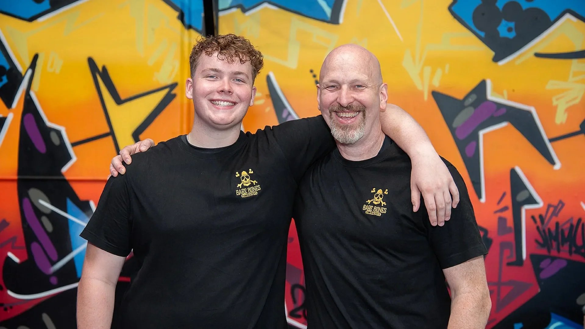 Two Raw Life Australia instructors smiling together in the gym in front of a colourful mural.