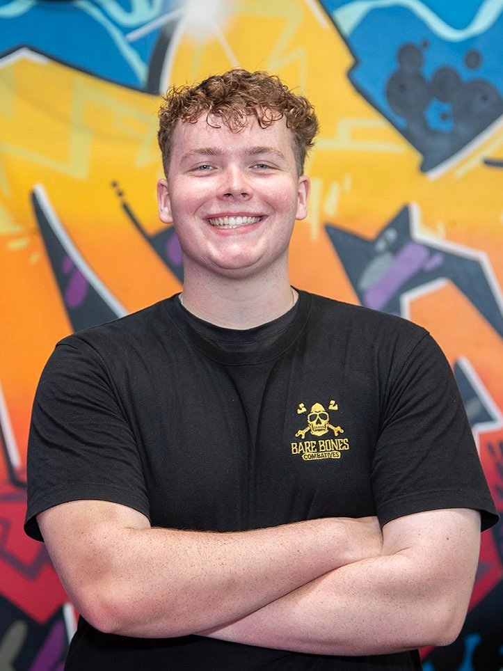 Geordie Armstrong, 1-on-1 coach at Raw Life Australia in Rowville, standing in front of a colourful graffiti wall.