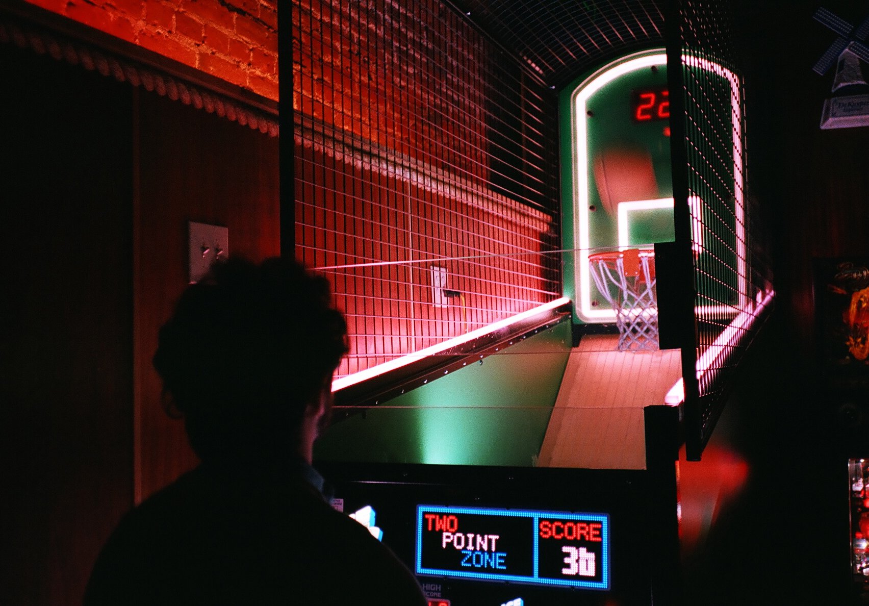 Person playing indoor basketball arcade game with electronic scoreboard showing score of 36 points.