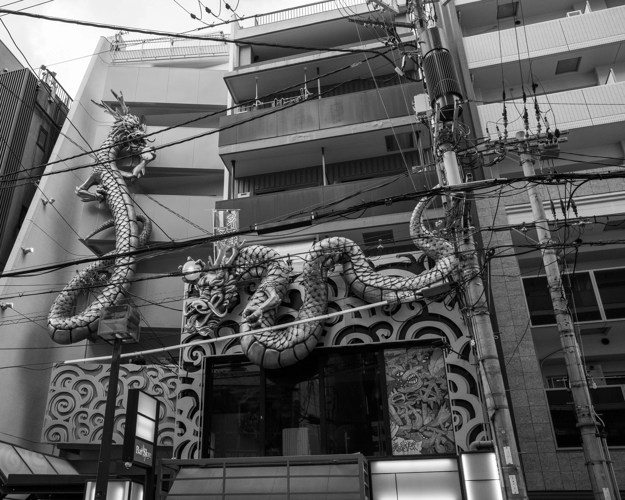 Black and white photo of a building facade with an ornate dragon sculpture and traditional Asian decorative elements.