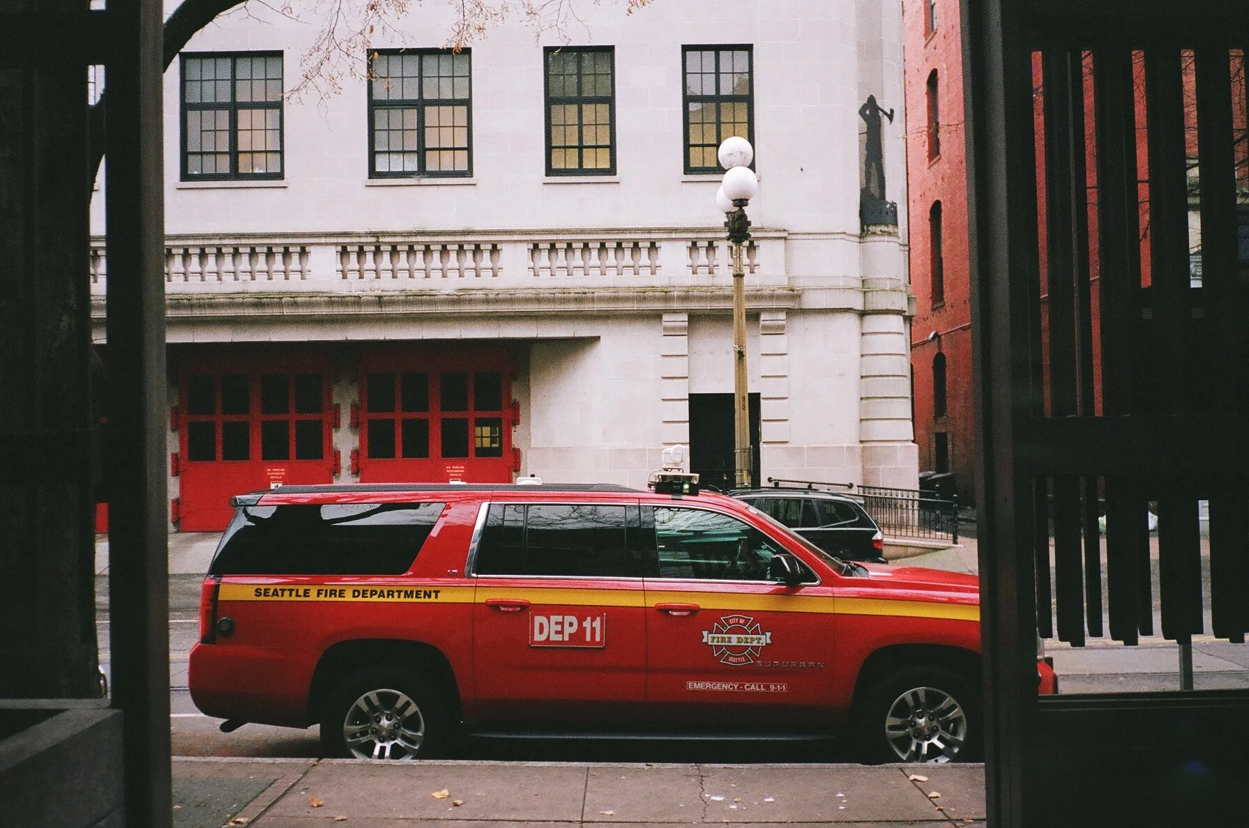 Red Seattle Fire Department vehicle parked on city street, view through an open gate