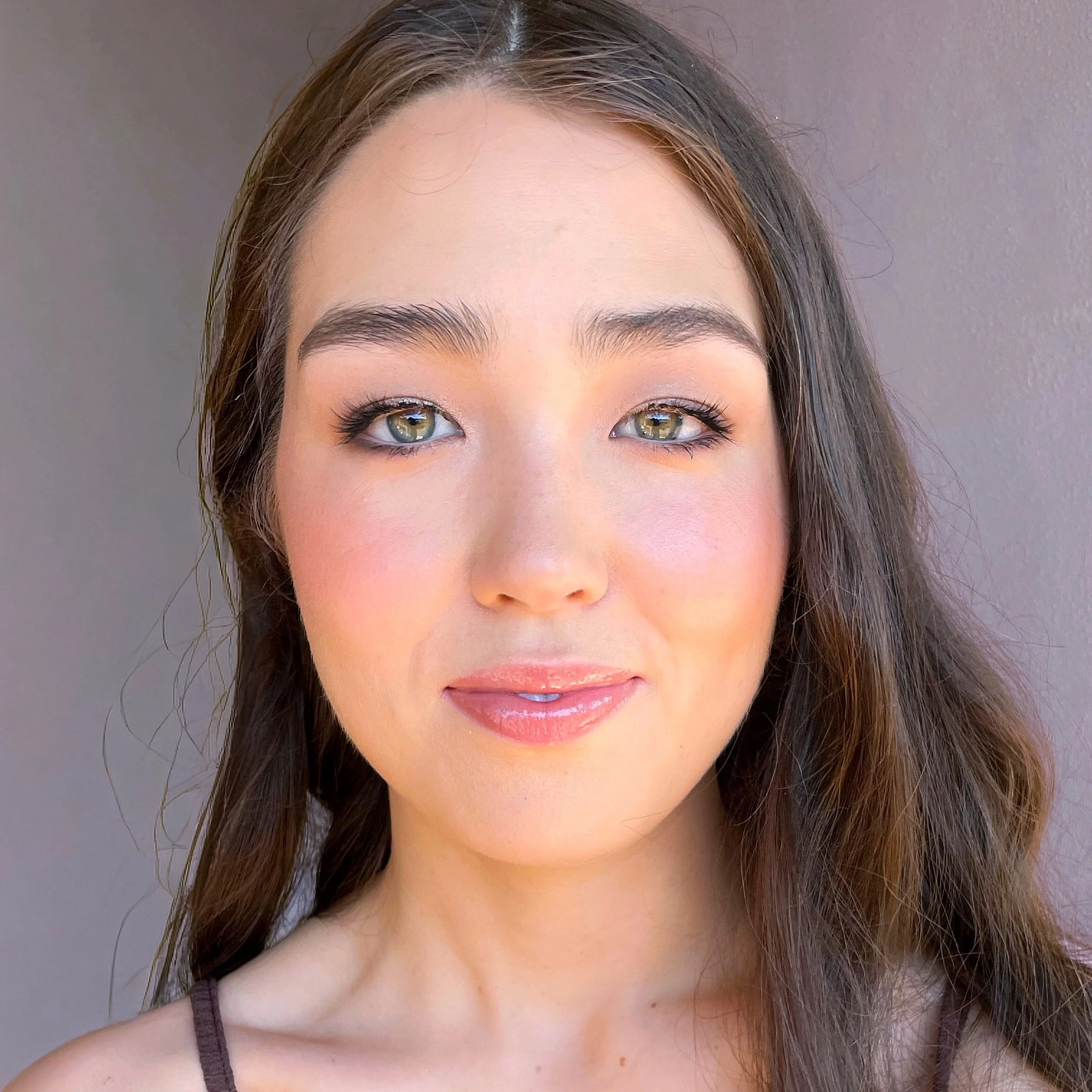 Young woman with fresh, rosy makeup and subtle shimmer highlighting her eyes and lips.