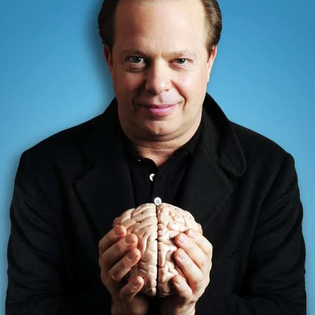 Person holding a model brain in front of a blue background.