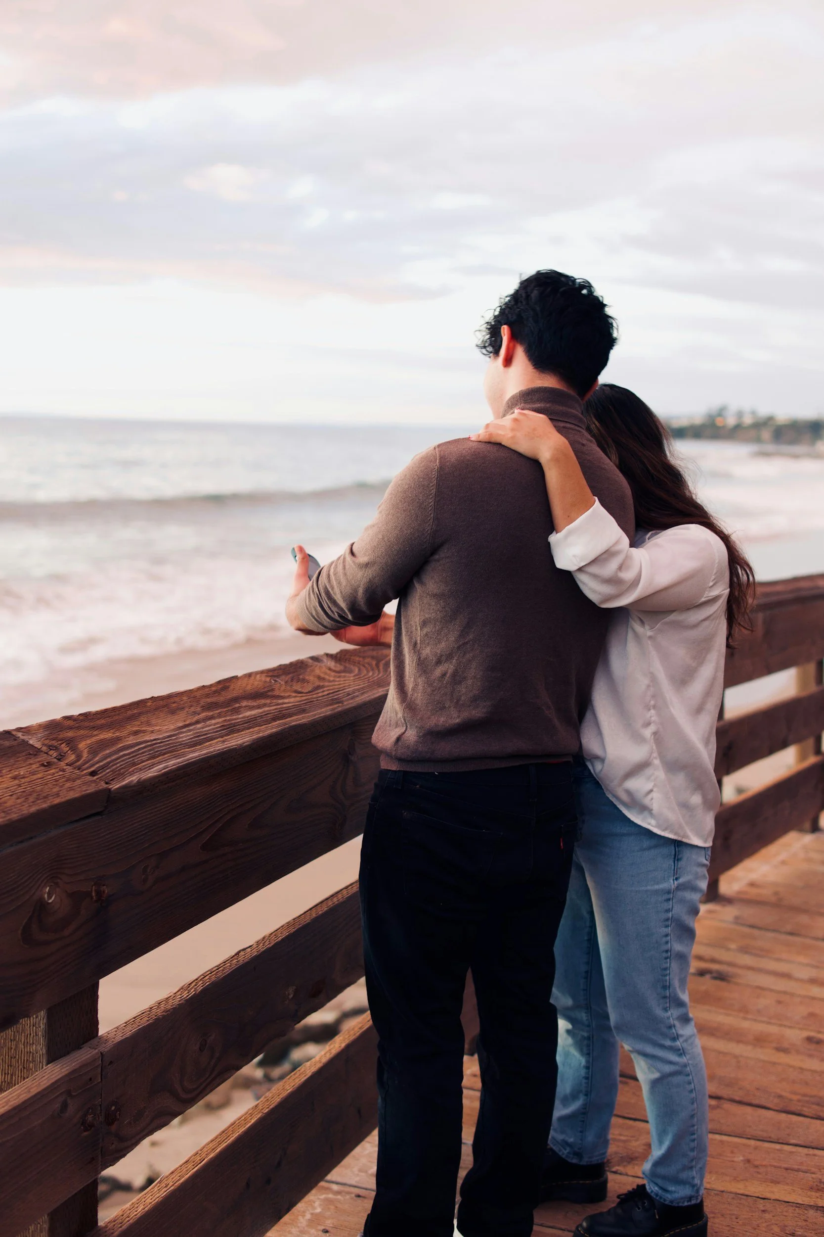 Couple standing together overlooking the ocean, representing connection, support, and the journey of building healthy relationships.