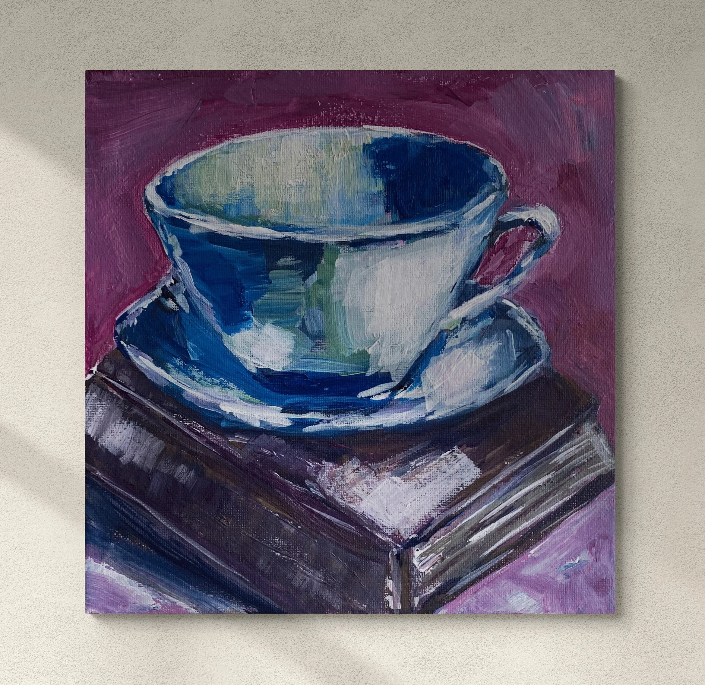 white coffee cup and saucer on brown book on purple background hung on wall.jpg