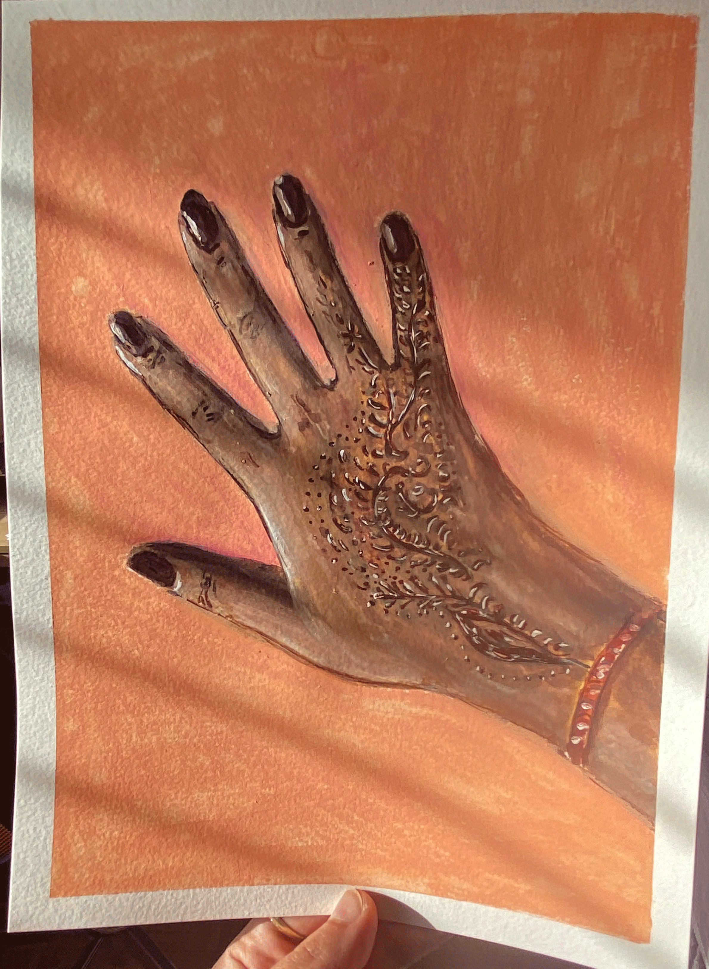 hand with brown henna tattoo on peach background in sunlight.png