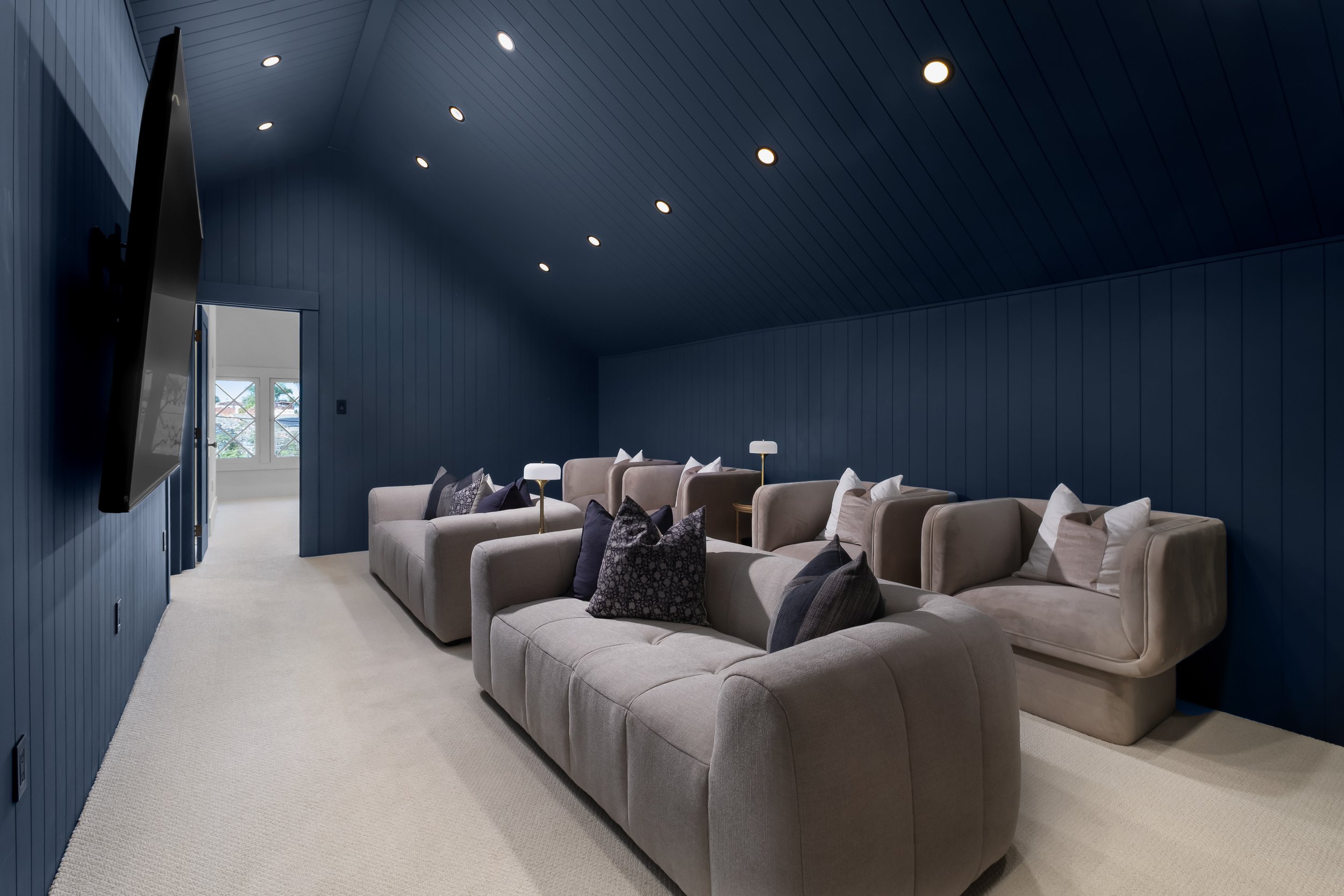 Living room with beige sectional sofa, pillows, lamps, and navy blue walls and ceiling.