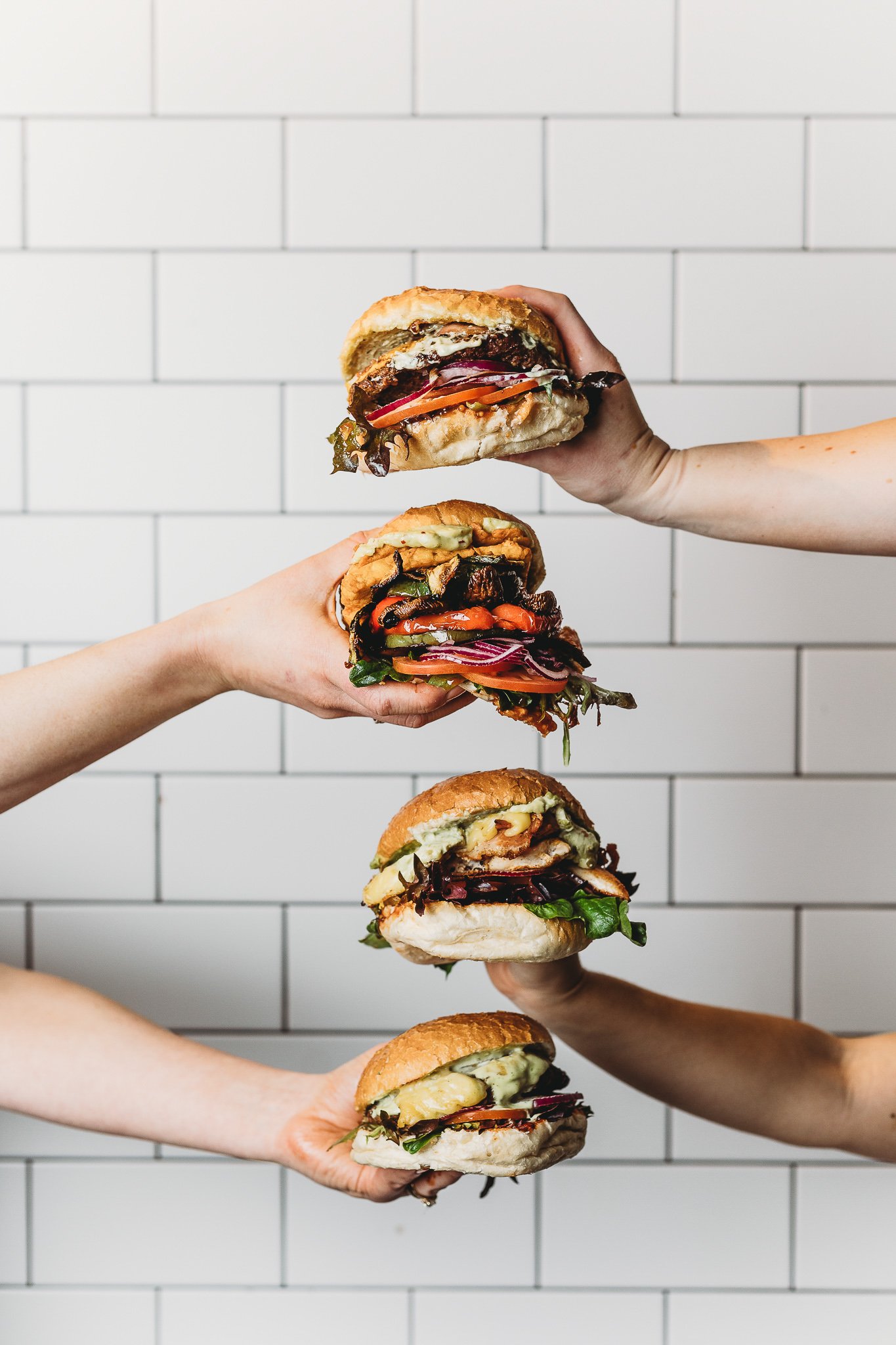 Canberra food photography - many hands hold burgers