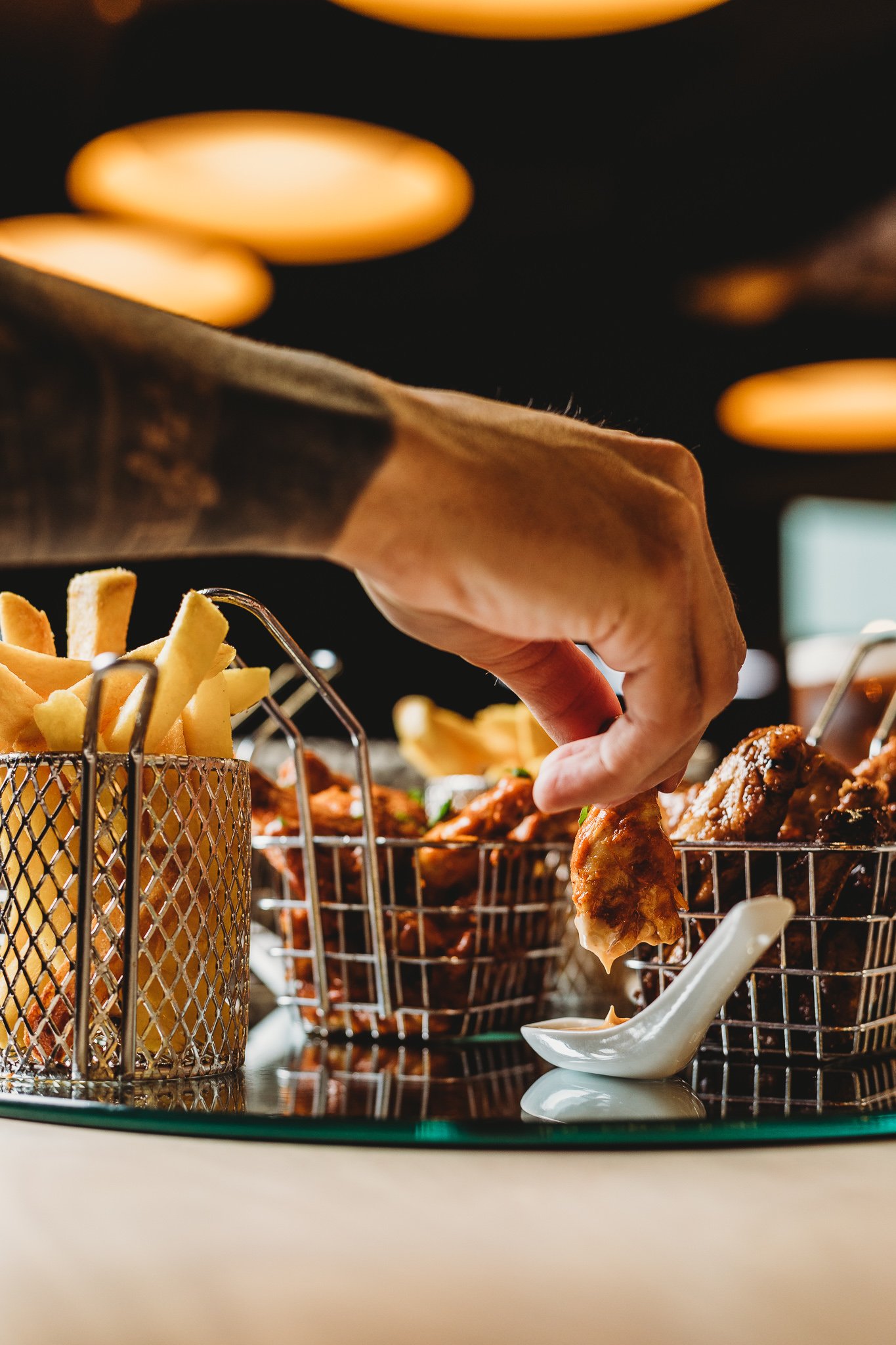 Canberra food photography - hand reaches for chicken wing