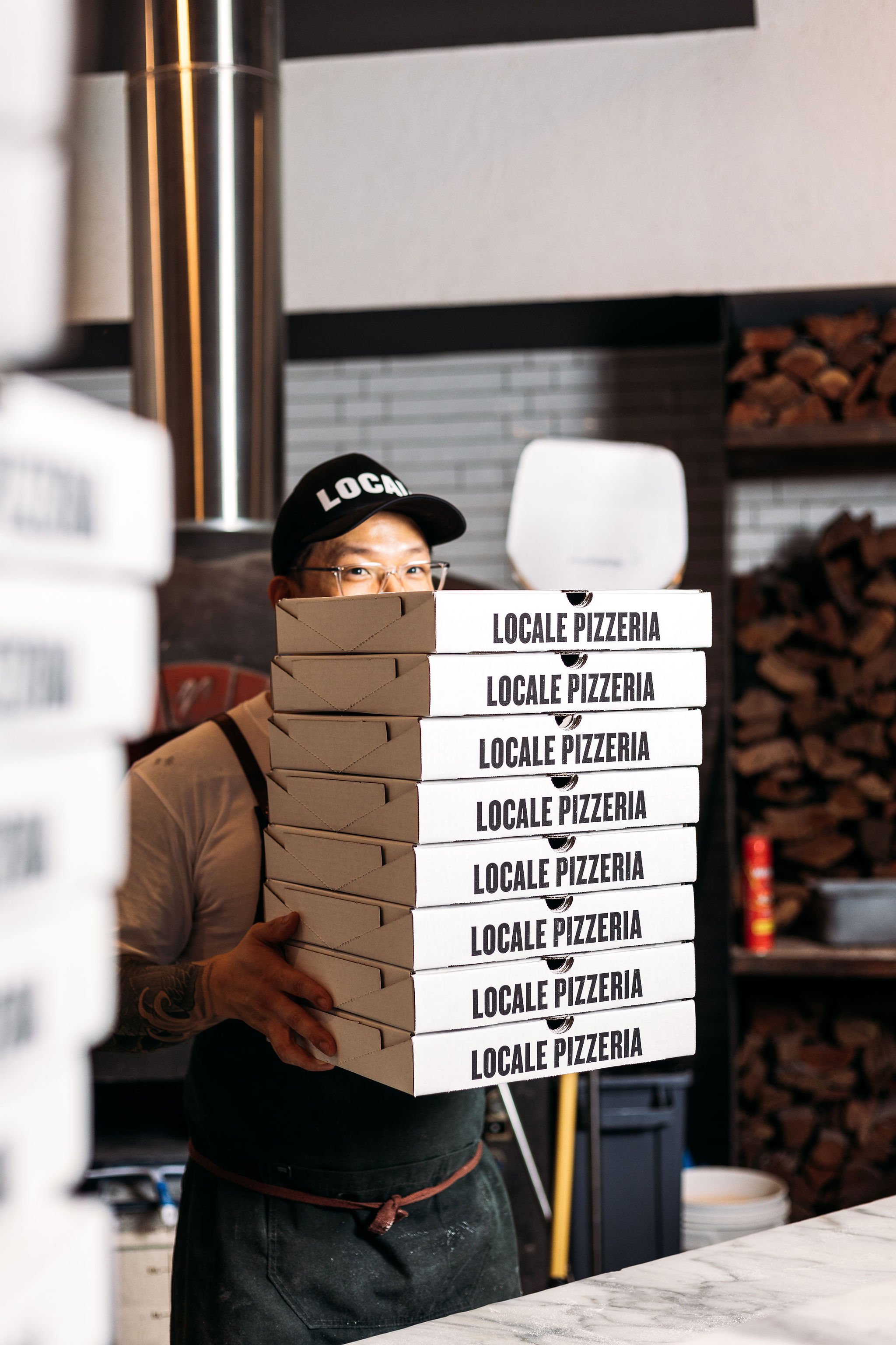 Canberra food photography - chef holds tower of pizza boxes