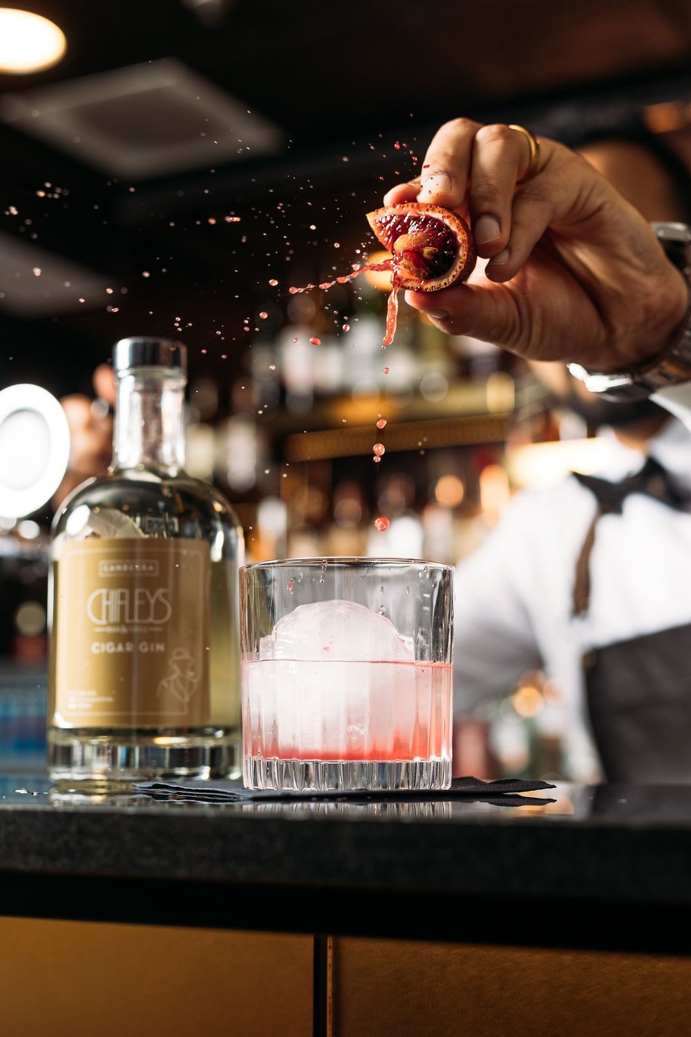 Canberra food photographer - bartender squeezes blood orange over cocktail