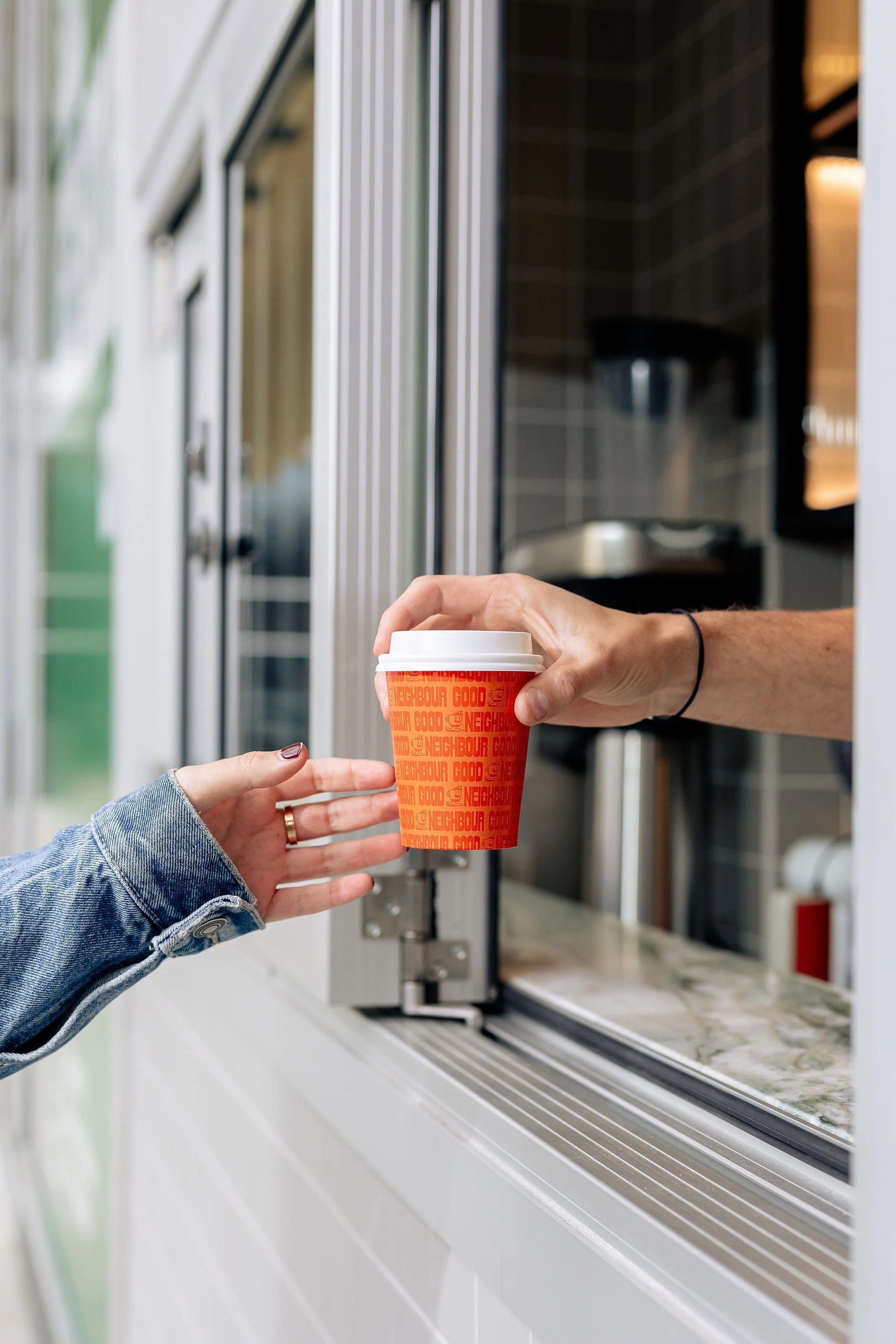 Canberra food photographer - hand passes coffee out window to customer