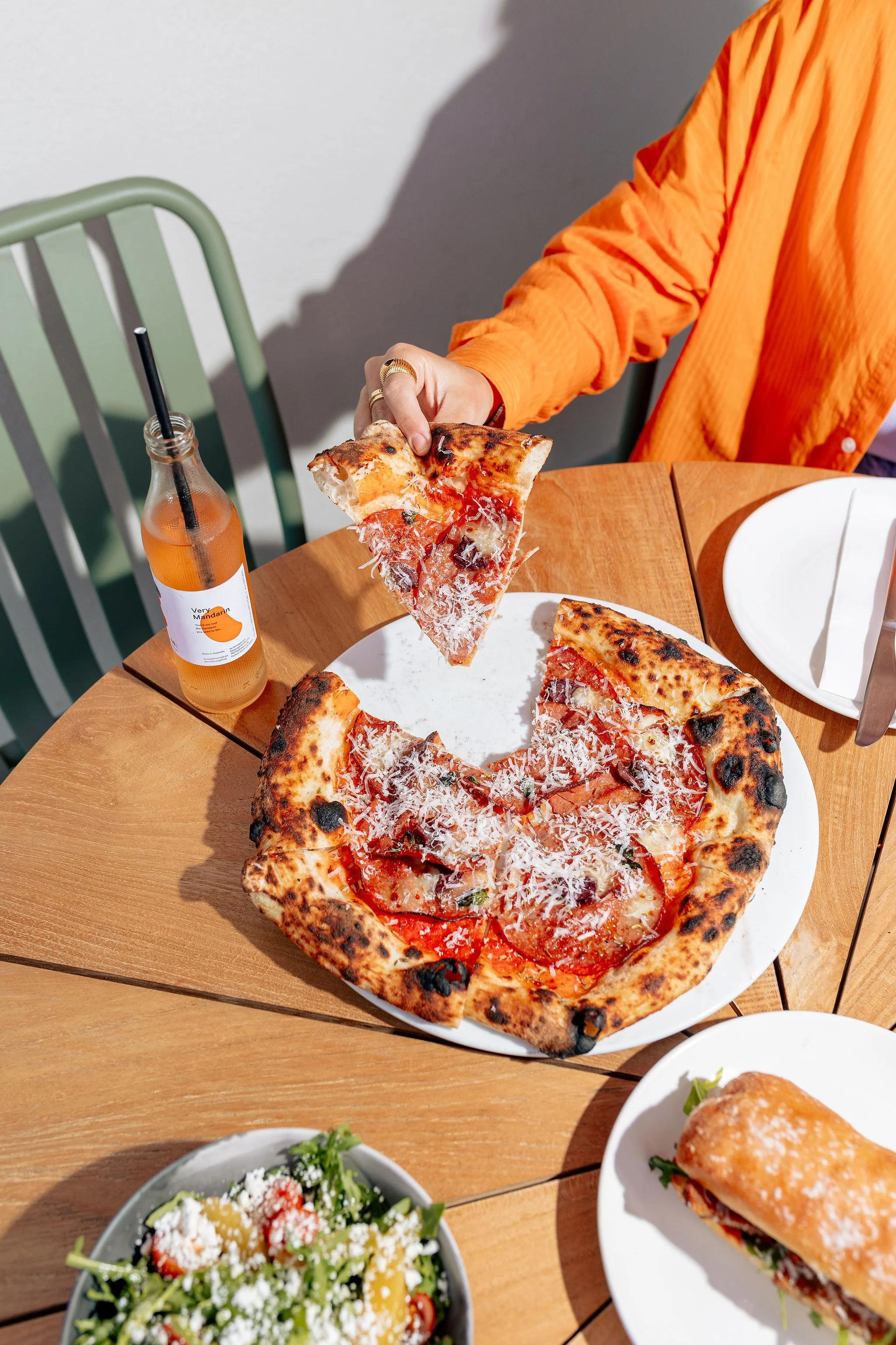 Hand lifts slice of pizza from plate