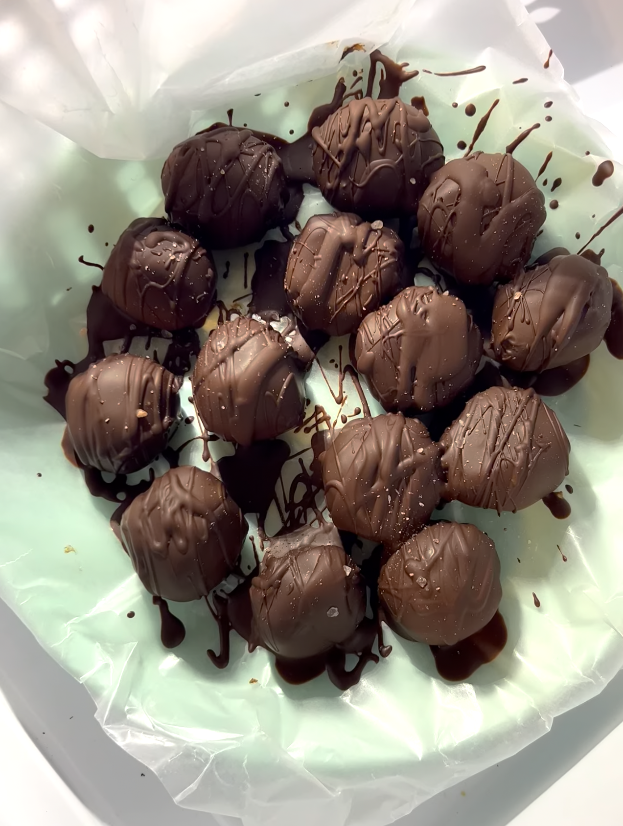 Chocolate chickpea truffles on top of parchment paper on a teal plate ready to eat.