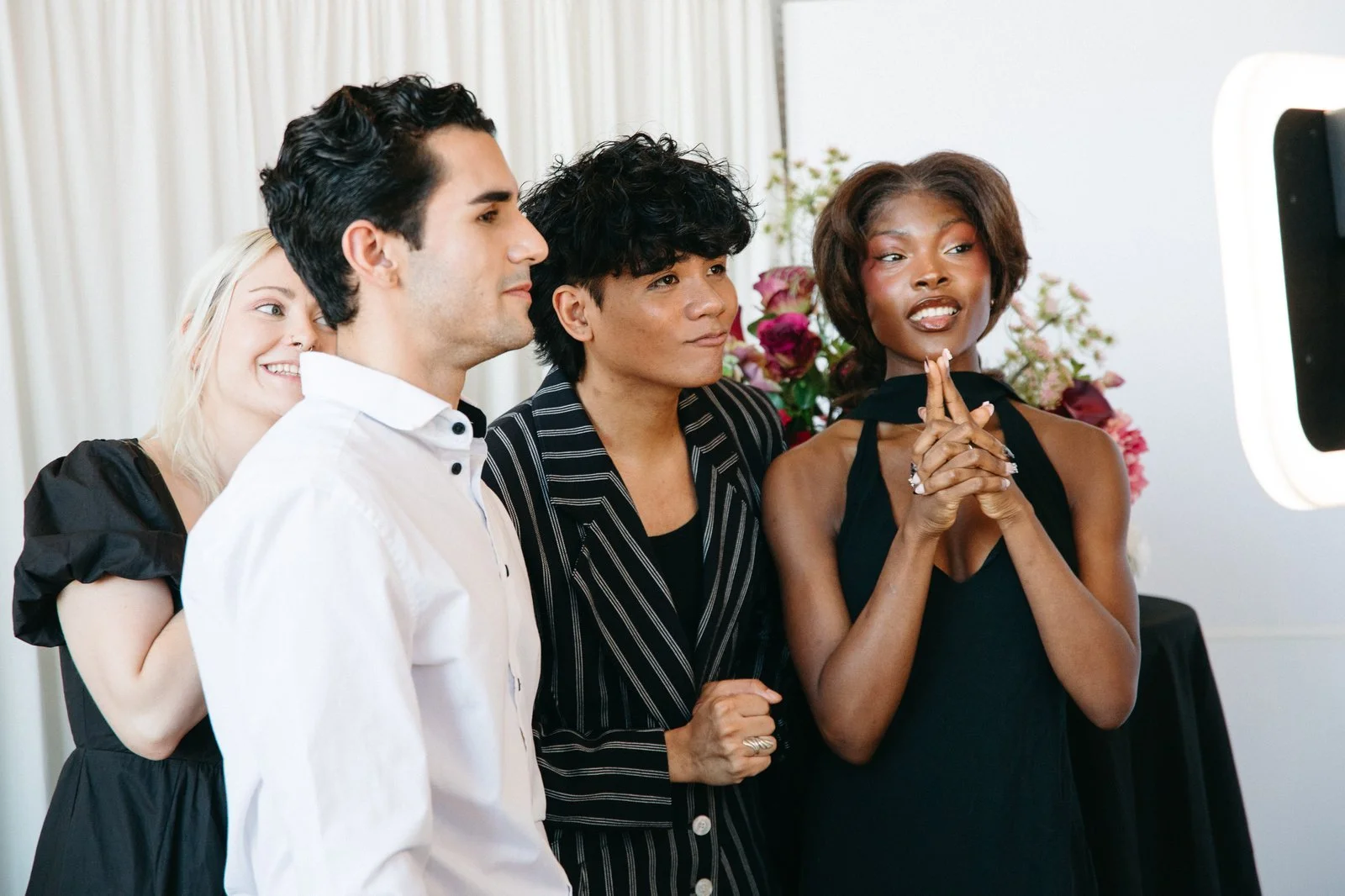 Four wedding guests burst into laughter together while waiting to record a message at the Voast booth.