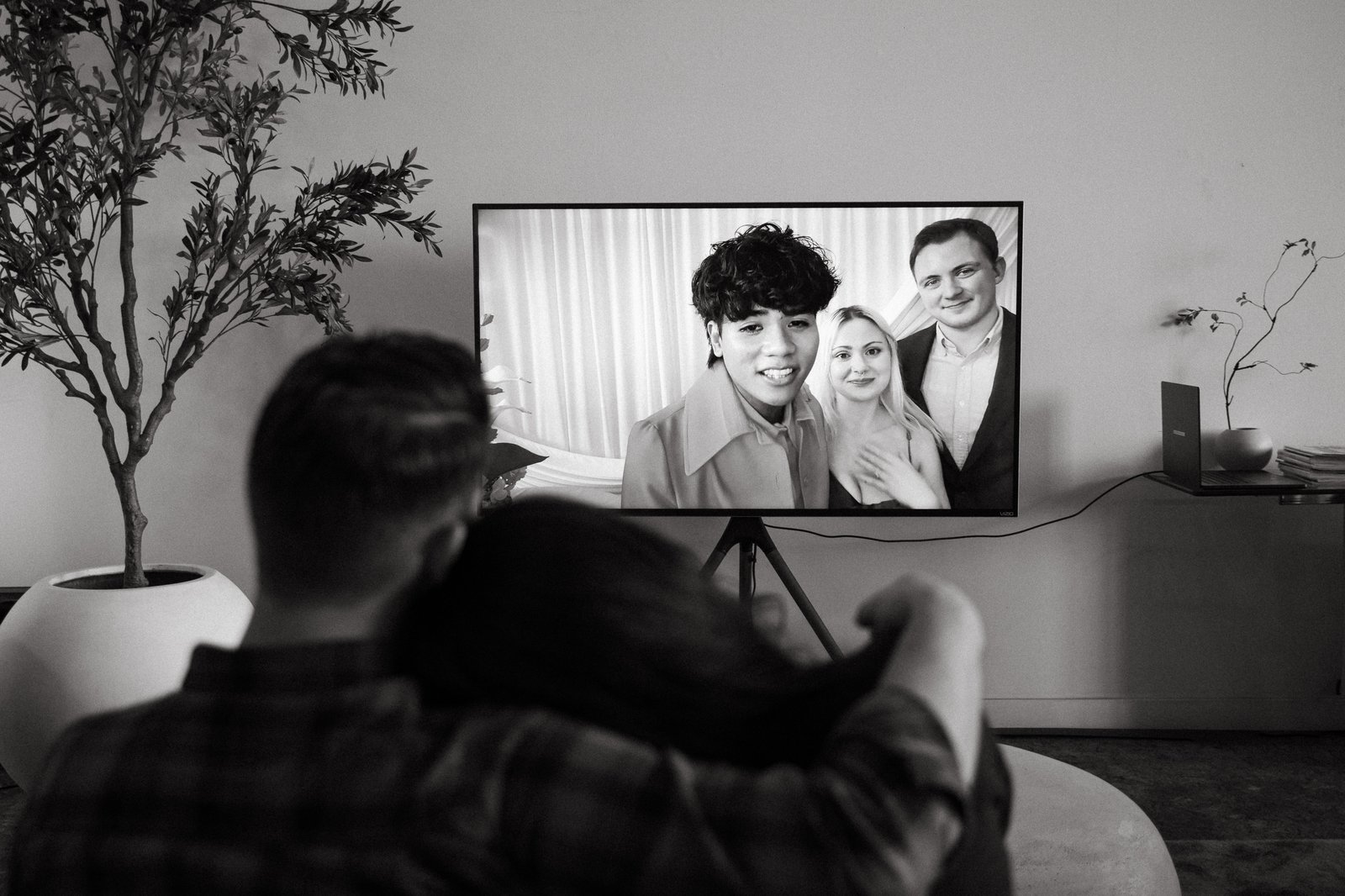 A couple cuddles on the couch, replaying a guest's Voast interview clip on their TV weeks after the wedding.