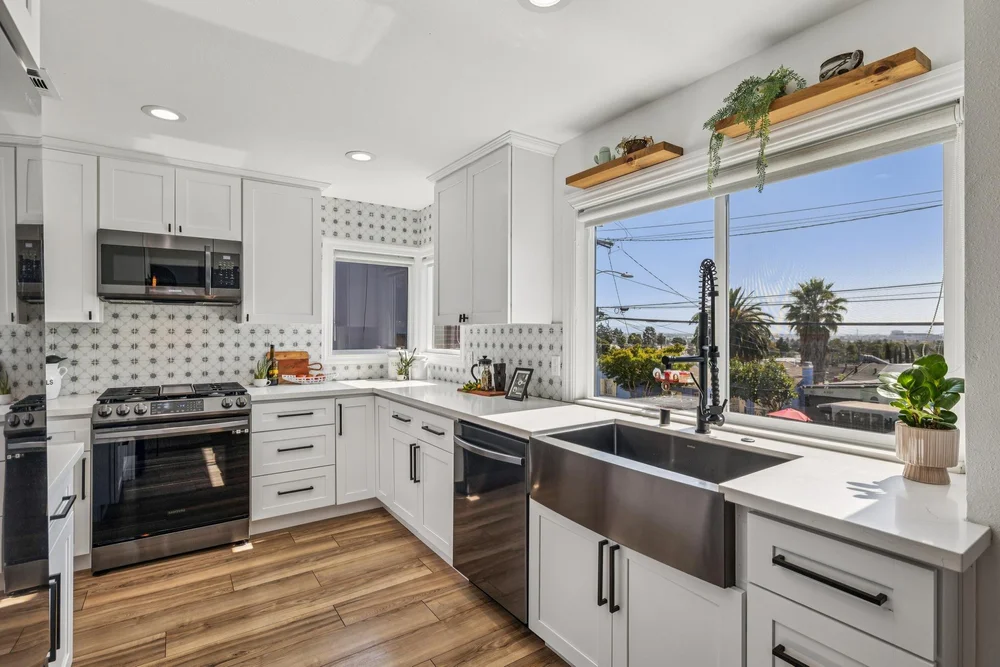 Bright kitchen with white cabinetry, a black sink and warm wood floating shelves