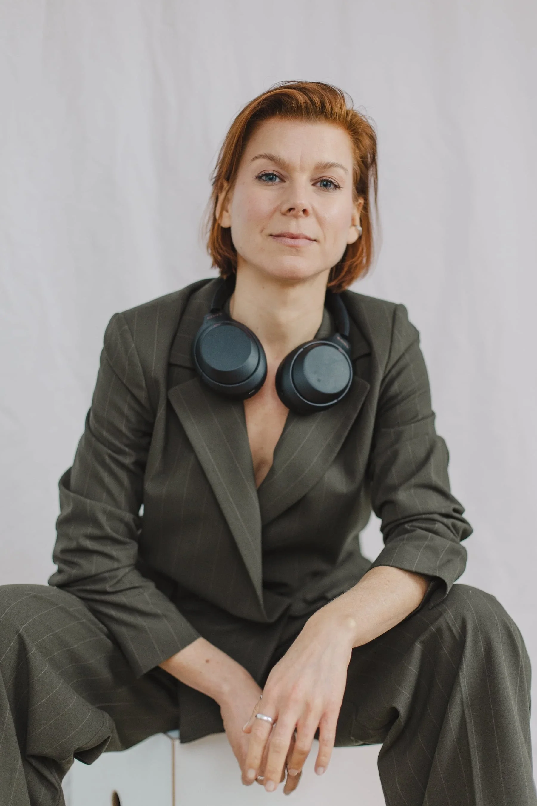 Kristina Appelt, Journalistin für Intersektionalen Feminismus, sitzt breitbeinig auf einem Stuhl und guckt direkt in die Kamera.