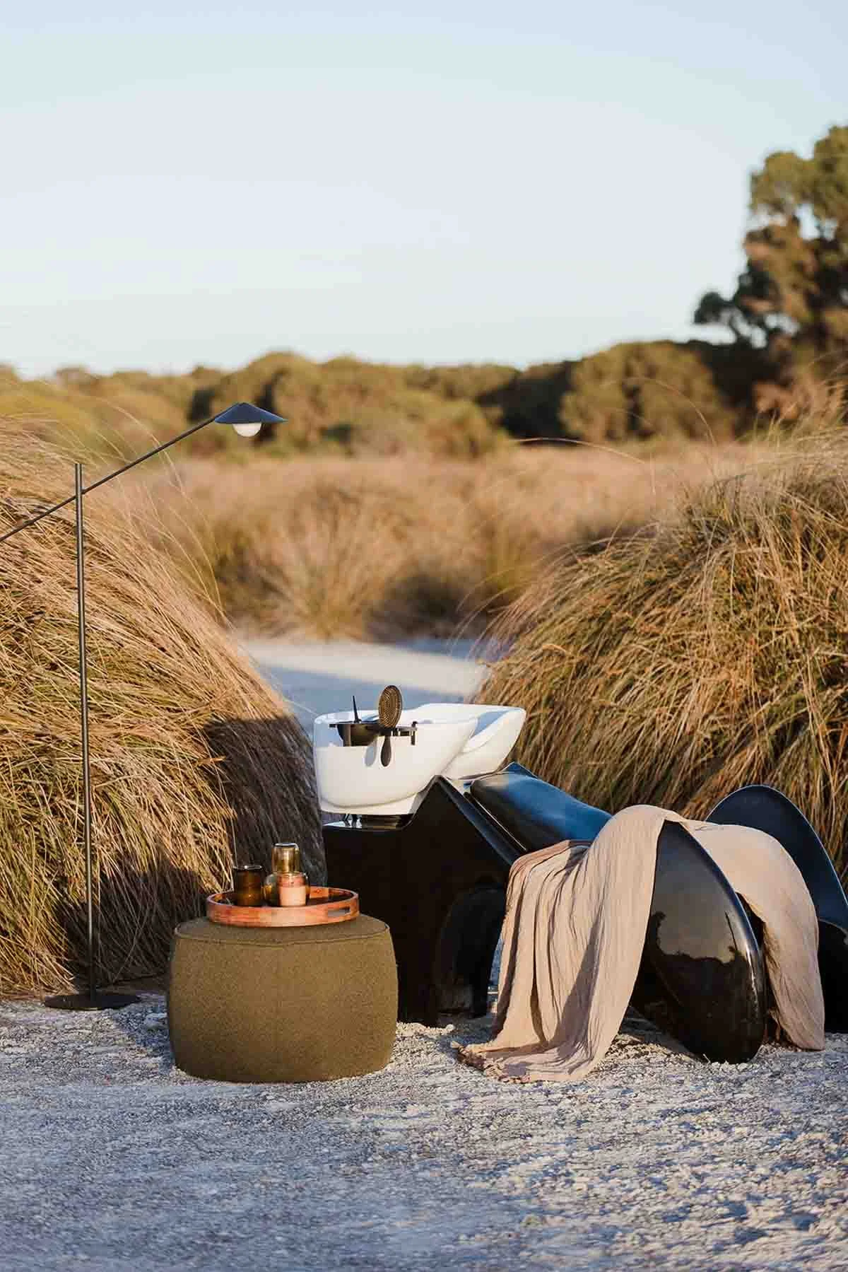 Hairdressing washing station with ottoman and tall lamp situated in a field during sunset, photographed by Clements + Co. Studio Photography.