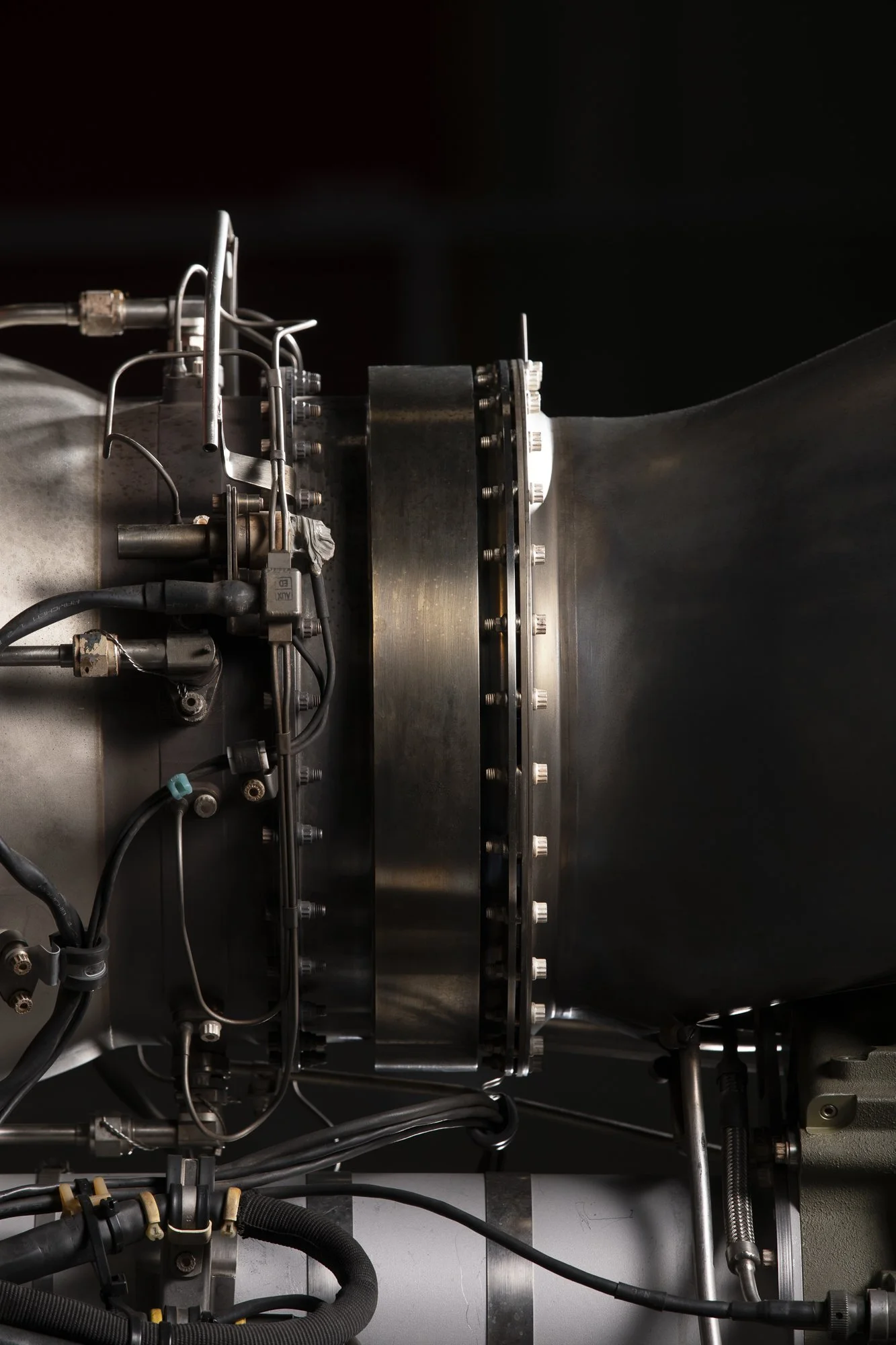 Partie d'un moteur ou d'une machine industrielle avec câbles, boulons et composantes métalliques.