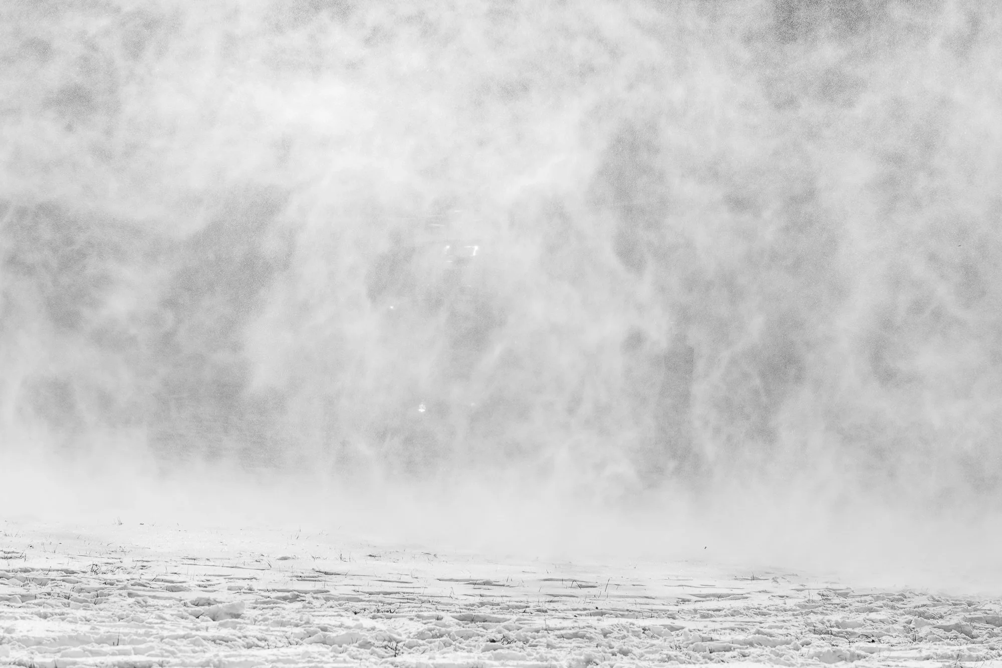 Neige soufflée par le vent dans un paysage enneigé avec un ciel nuageux