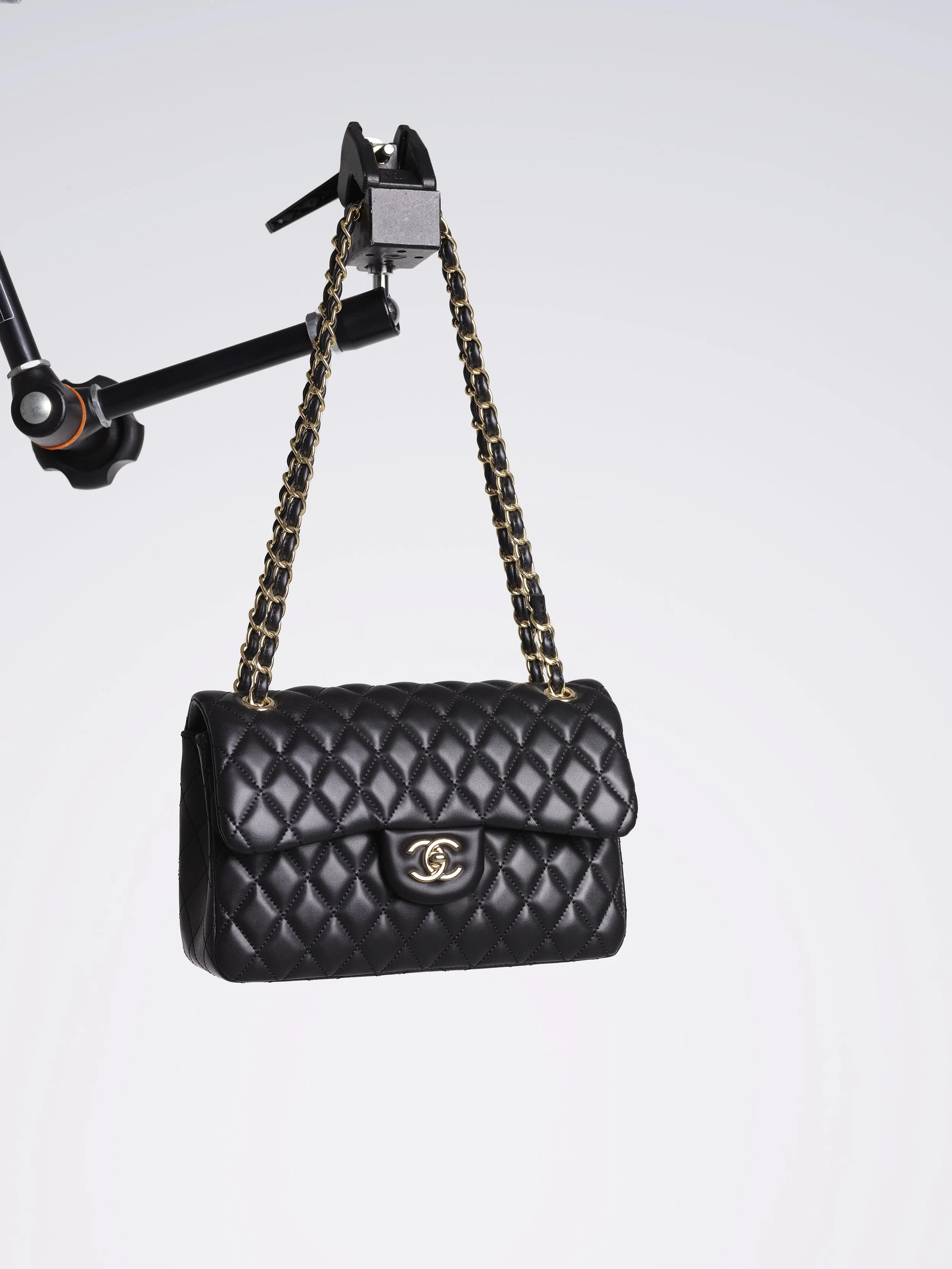 Sac à main noir en cuir matelassé avec chaîne dorée et logo Chanel en avant.