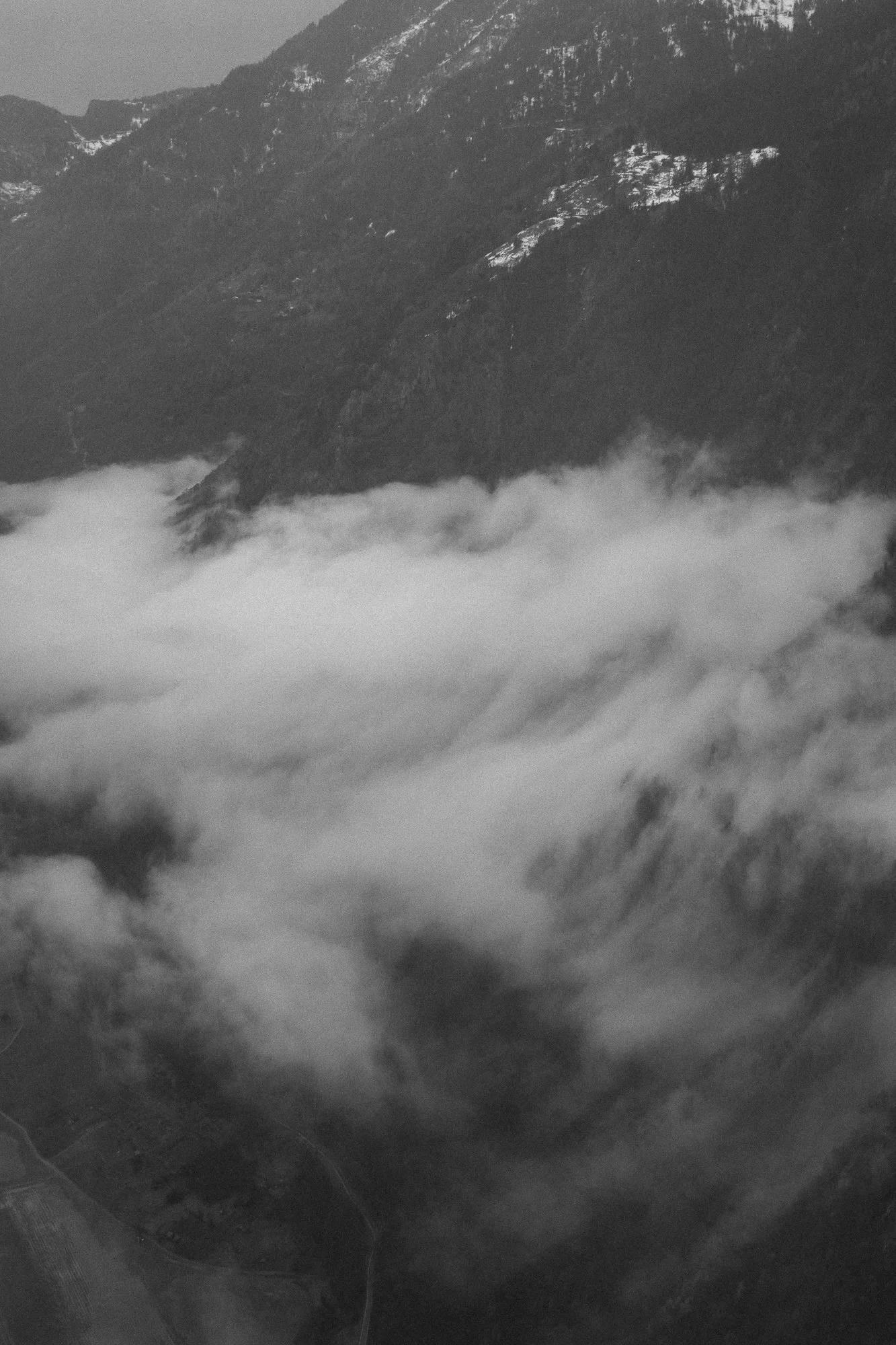 Montagnes avec sommets enneigés et nuages enveloppant la vallée.