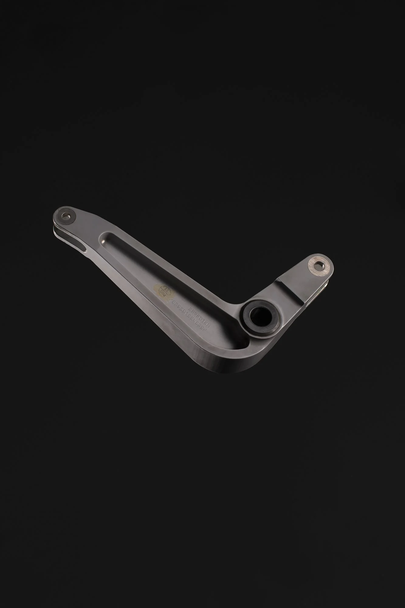 Pièce mécanique en métal, probablement une pièce de machine ou de véhicule, placée sur un fond noir.