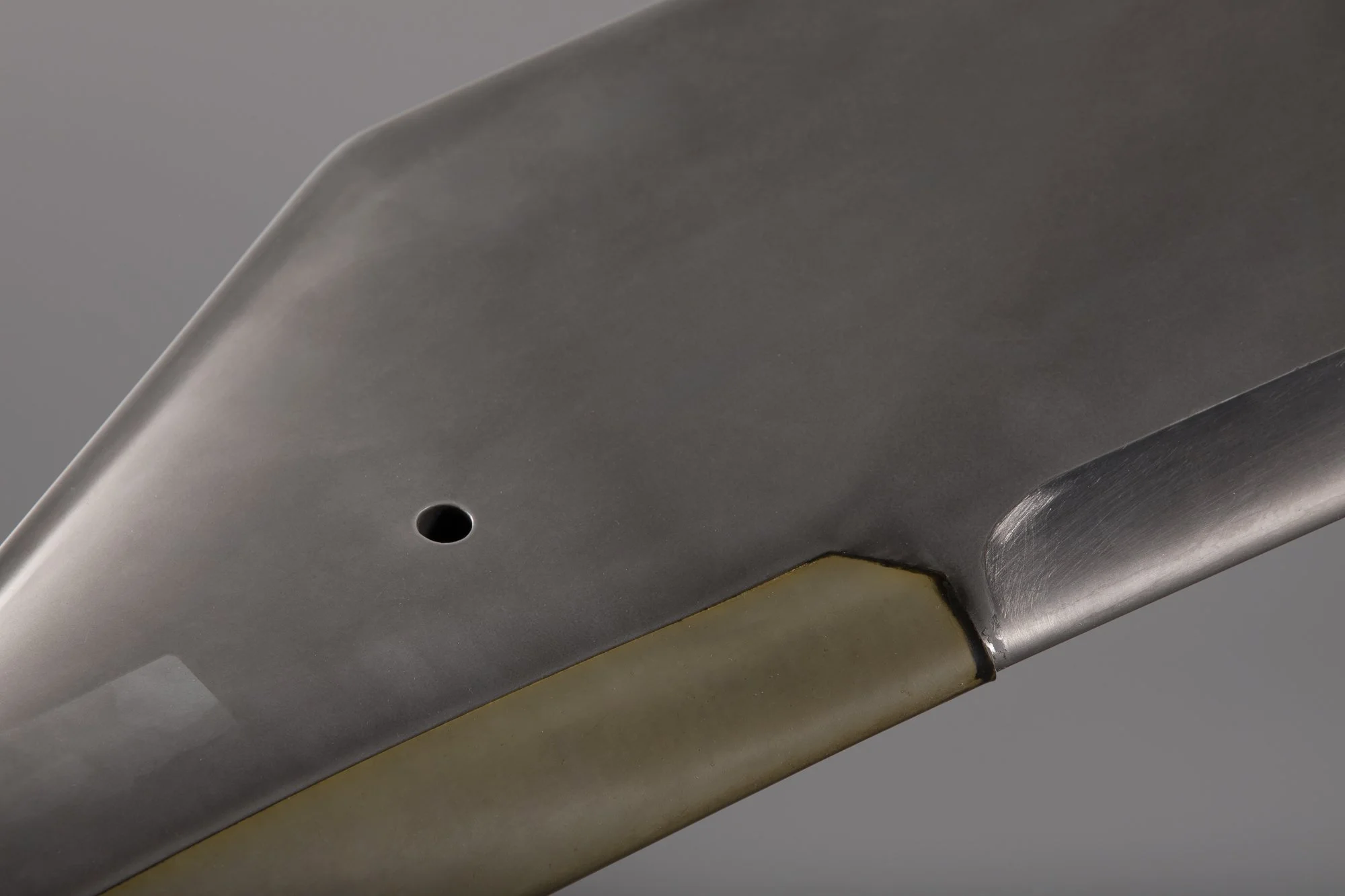 Close-up d'une lame de couteau en métal avec un manche en plastique beige.