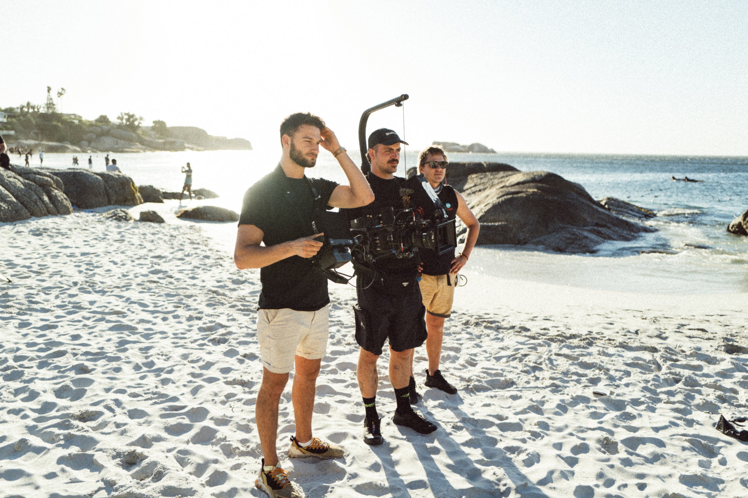 Three filmmakers on a beach with a camera rig.