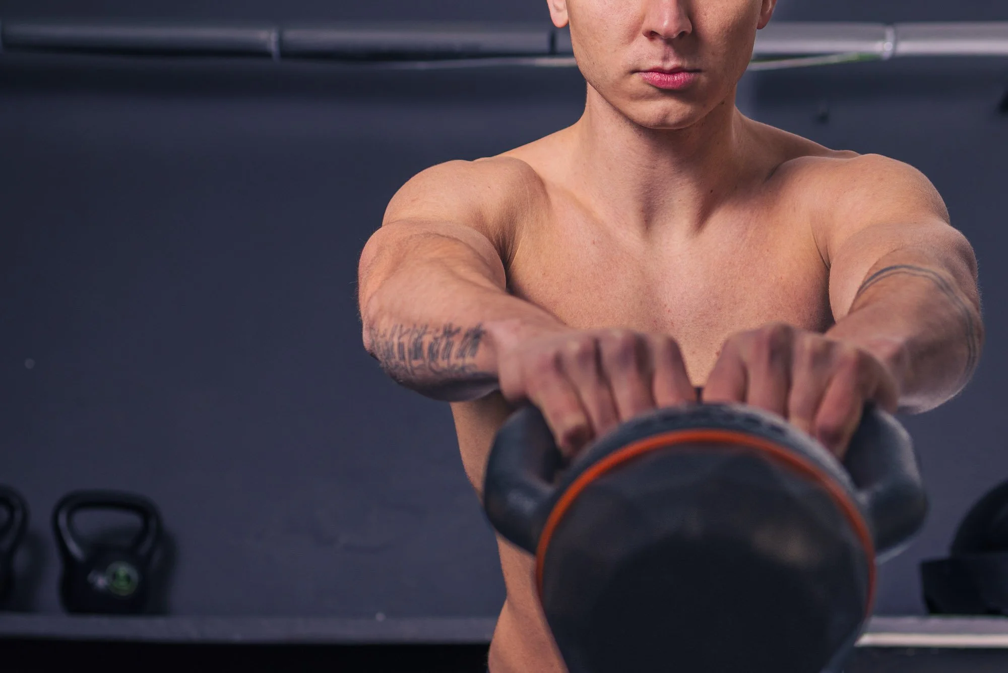 Personal trainer performing kettlebell exercise in gym with strong arms and focused posture, representing professional fitness content and strength training visuals, fitness branding